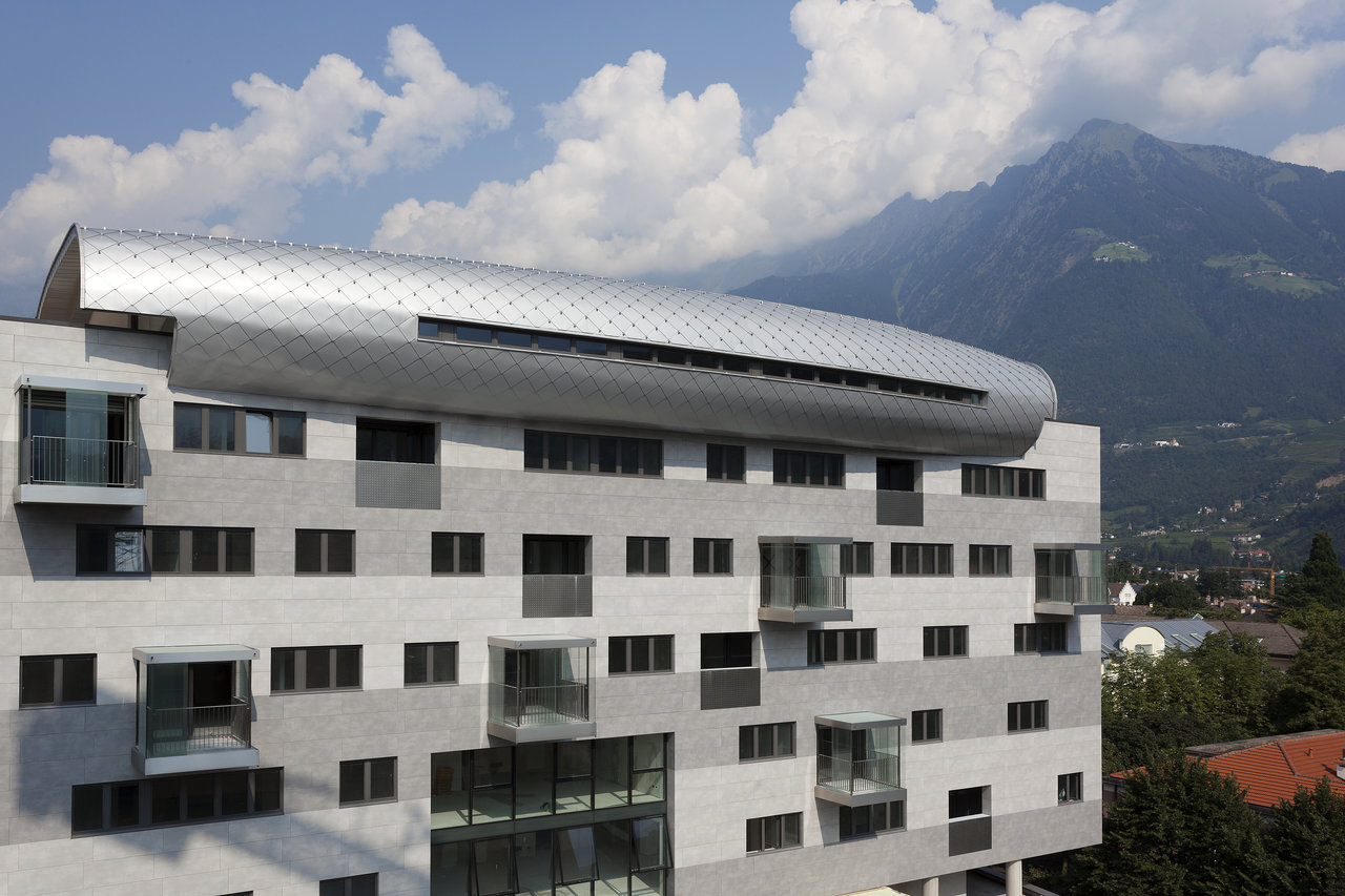 Modern Architecture: Building with grey facade panels and curved metal roof.