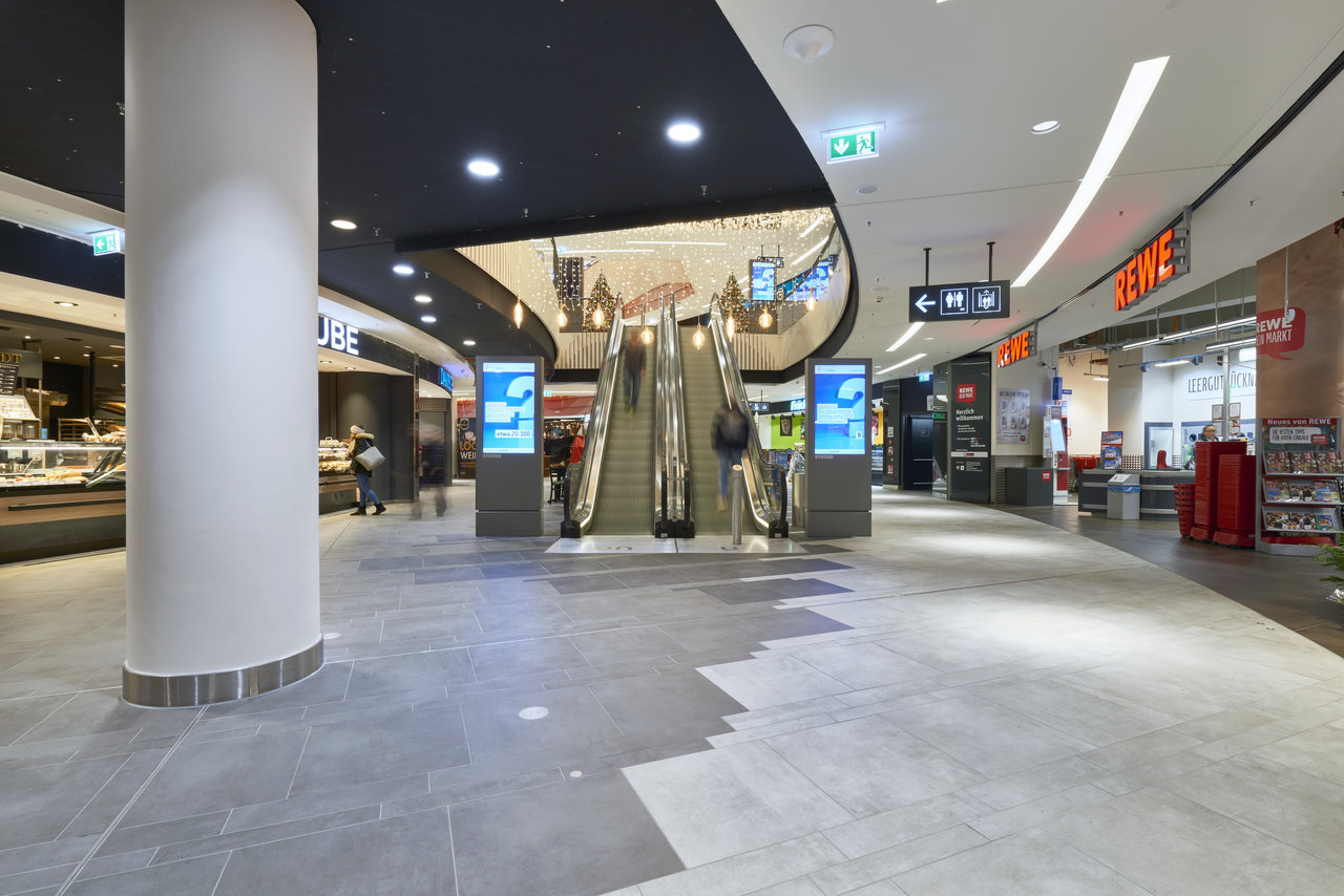 Grey large-format tiles with light and dark pattern in a modern shopping arcade.