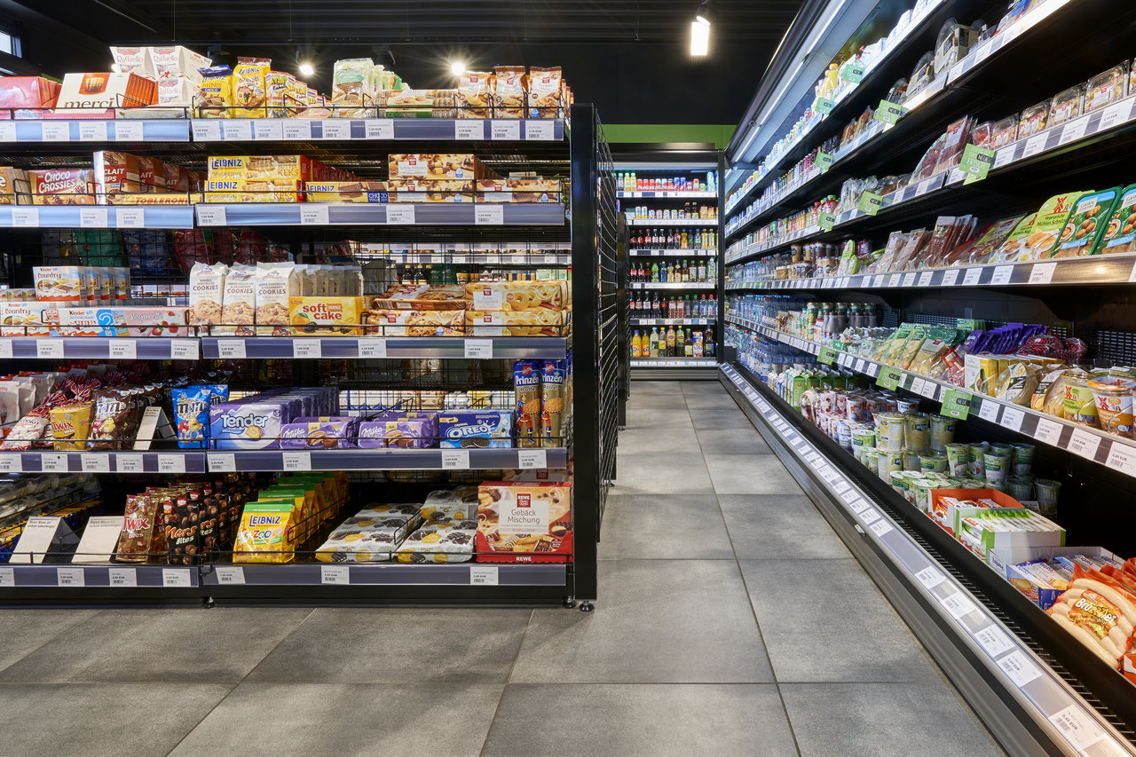 Modern supermarket aisle with large-format grey floor tiles.