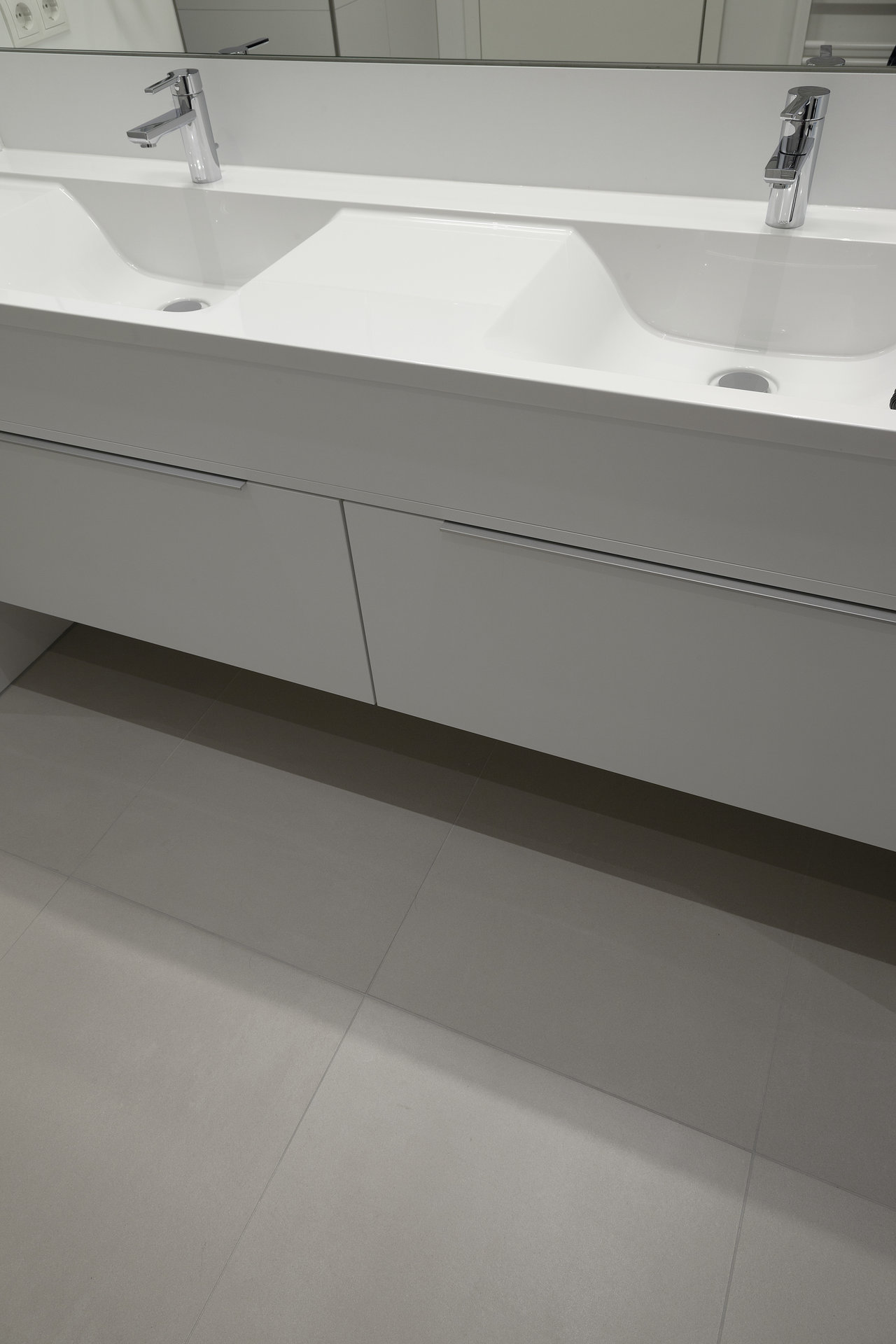 Bright, large-format floor tiles in a modern bathroom with a double vanity.