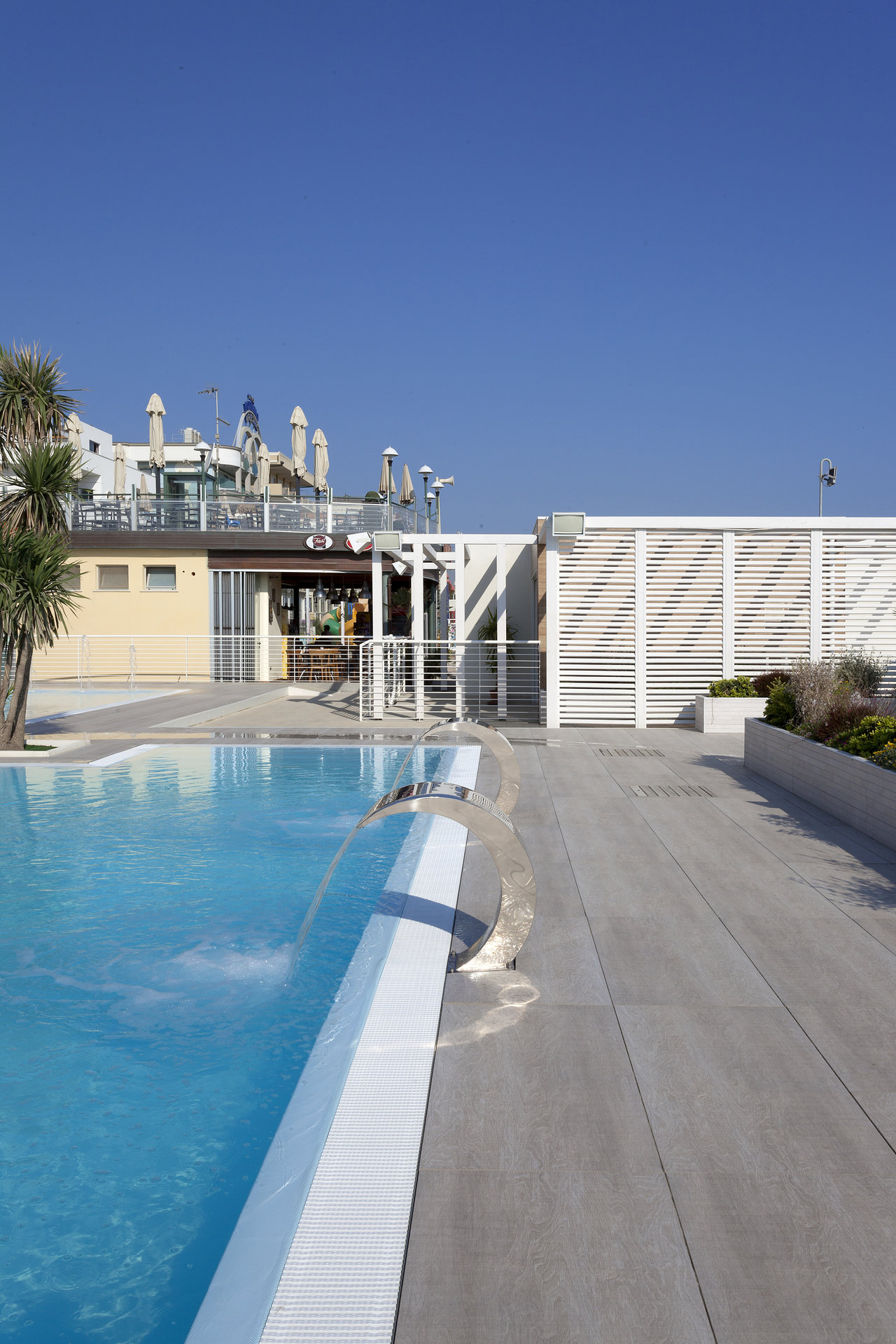 Stylish outdoor tiles in light concrete look by the pool for exclusive terraces.