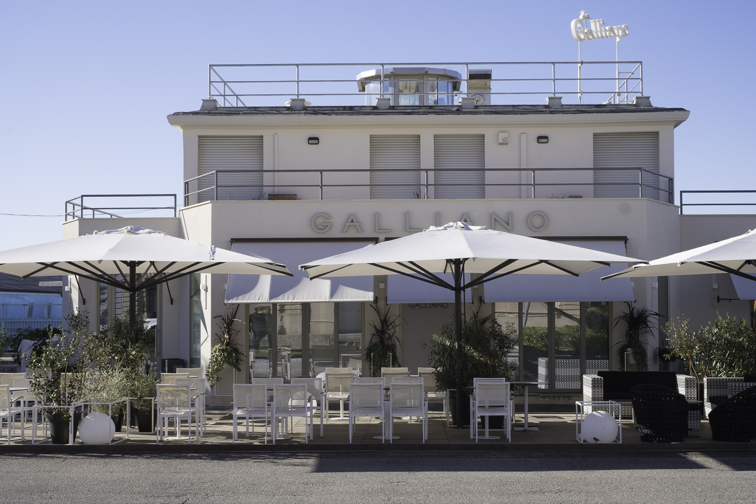 Modern outdoor terrace with white furniture and parasols, perfect for high-quality outdoor tiles.