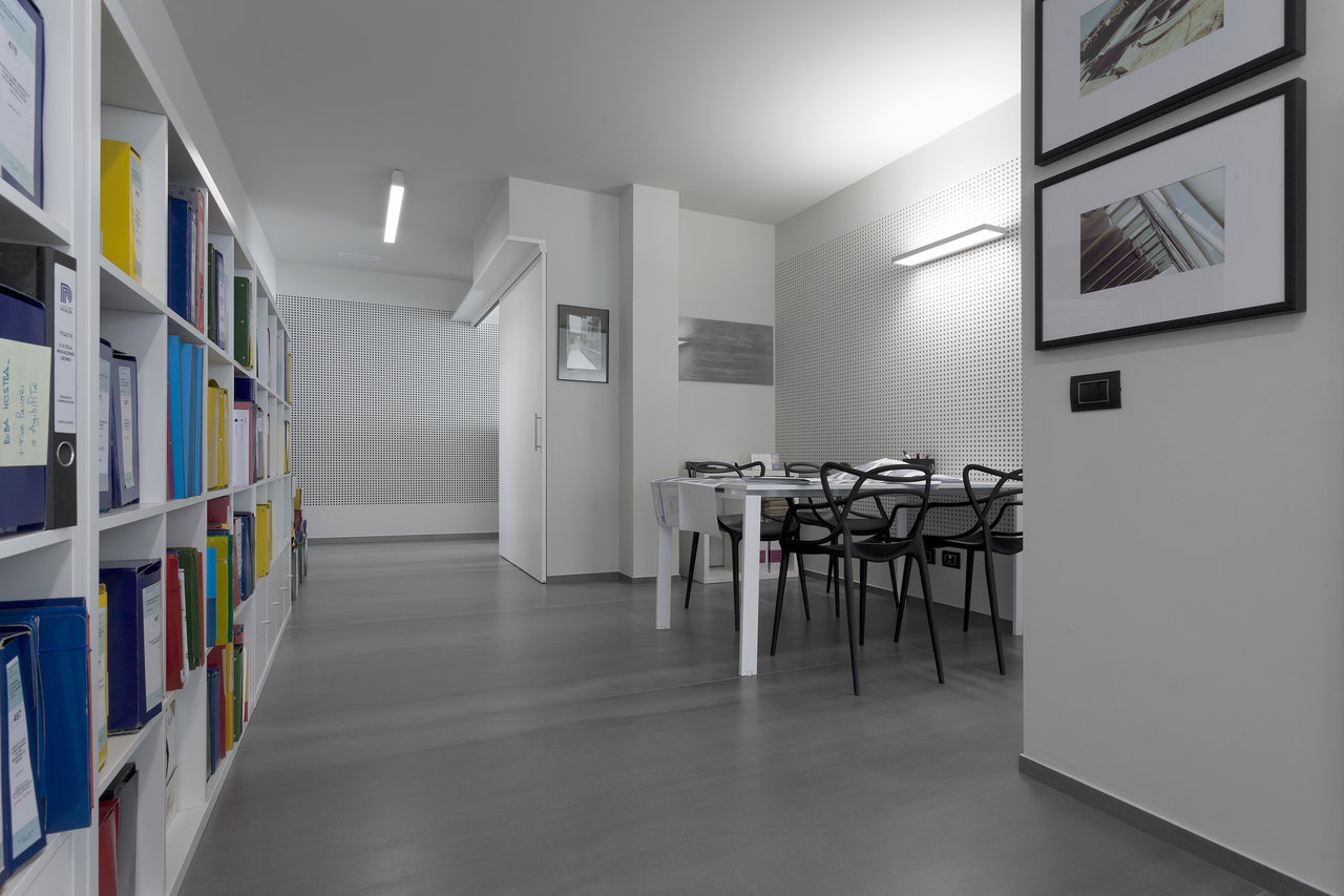 Elegant grey tiled floor in a modern office with a bookshelf and meeting corner.