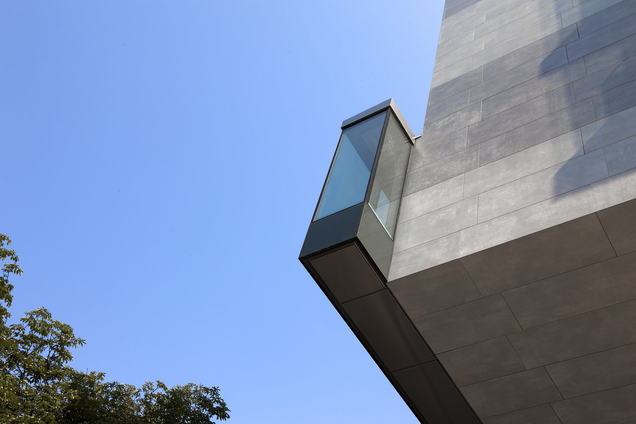 Modern tiled facade with a striking glass bay window.