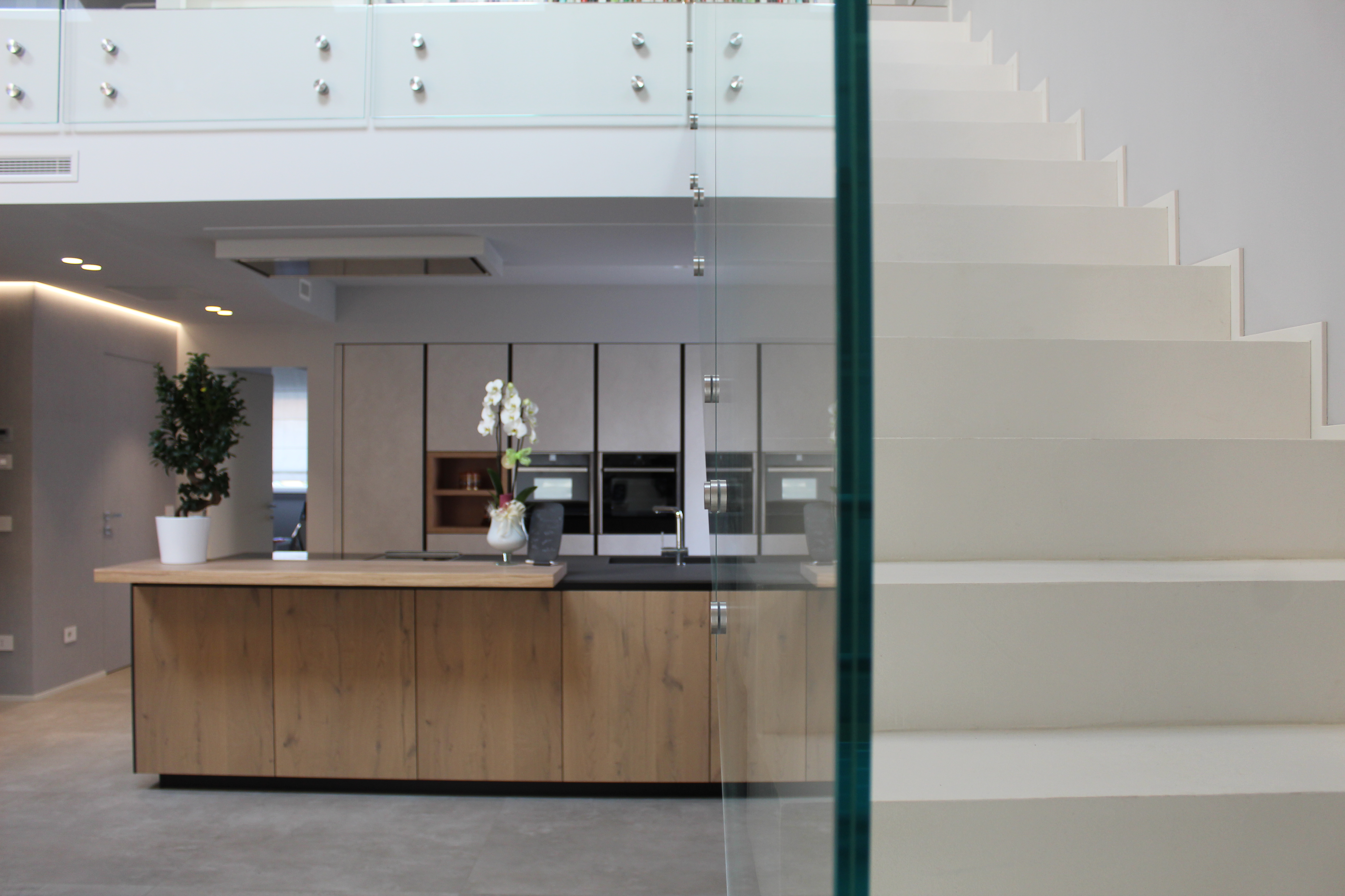 Bright living area with modern kitchen, stairs, and large-format tiles.