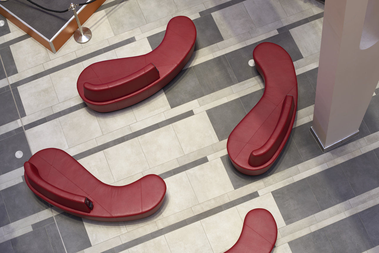 Grey and anthracite striped floor tiles with red designer armchairs.