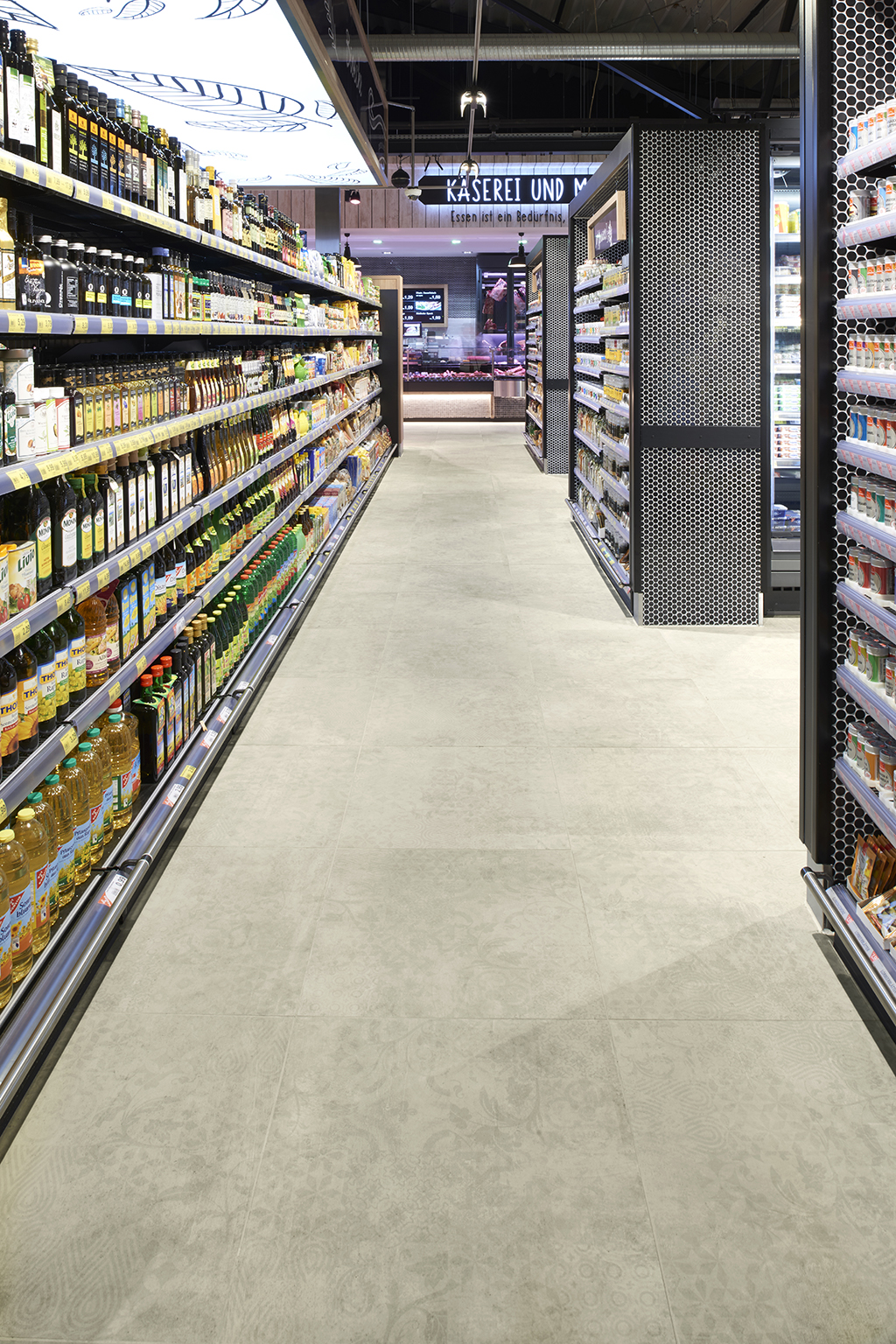 Light, large-format floor tiles in a supermarket aisle.