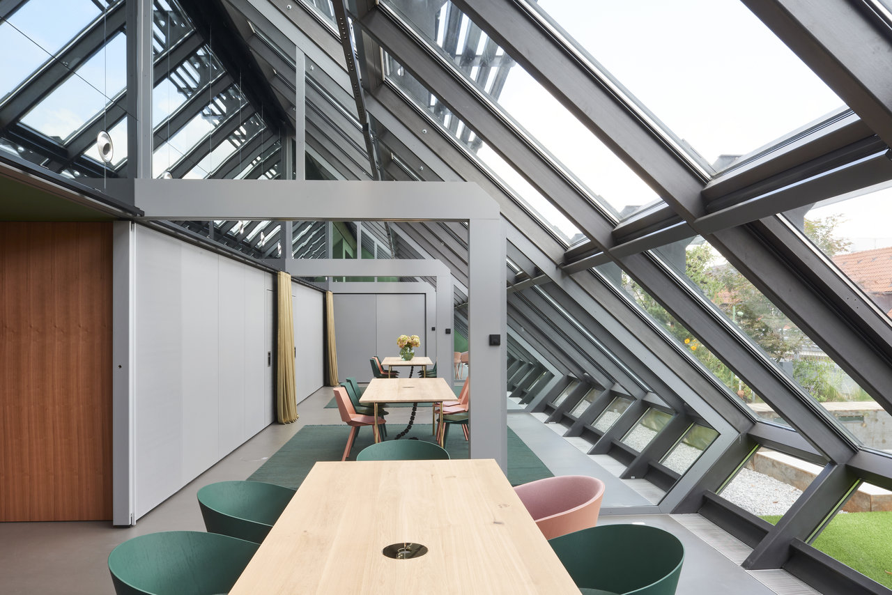 Bright, modern room with a glass roof, wooden tables, and stylish flooring.