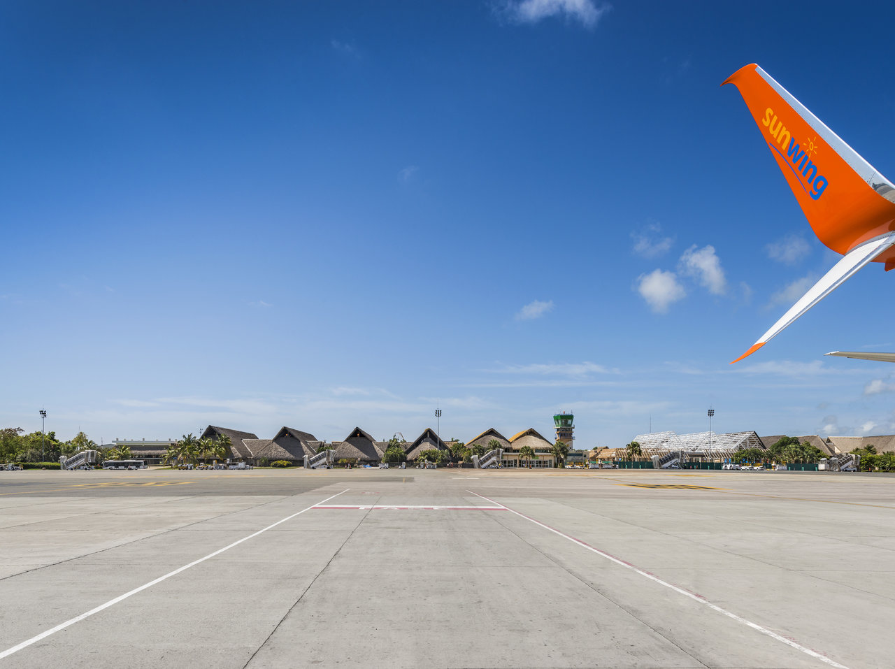 Sunny airport apron, Sunwing plane tail, exotic terminals.