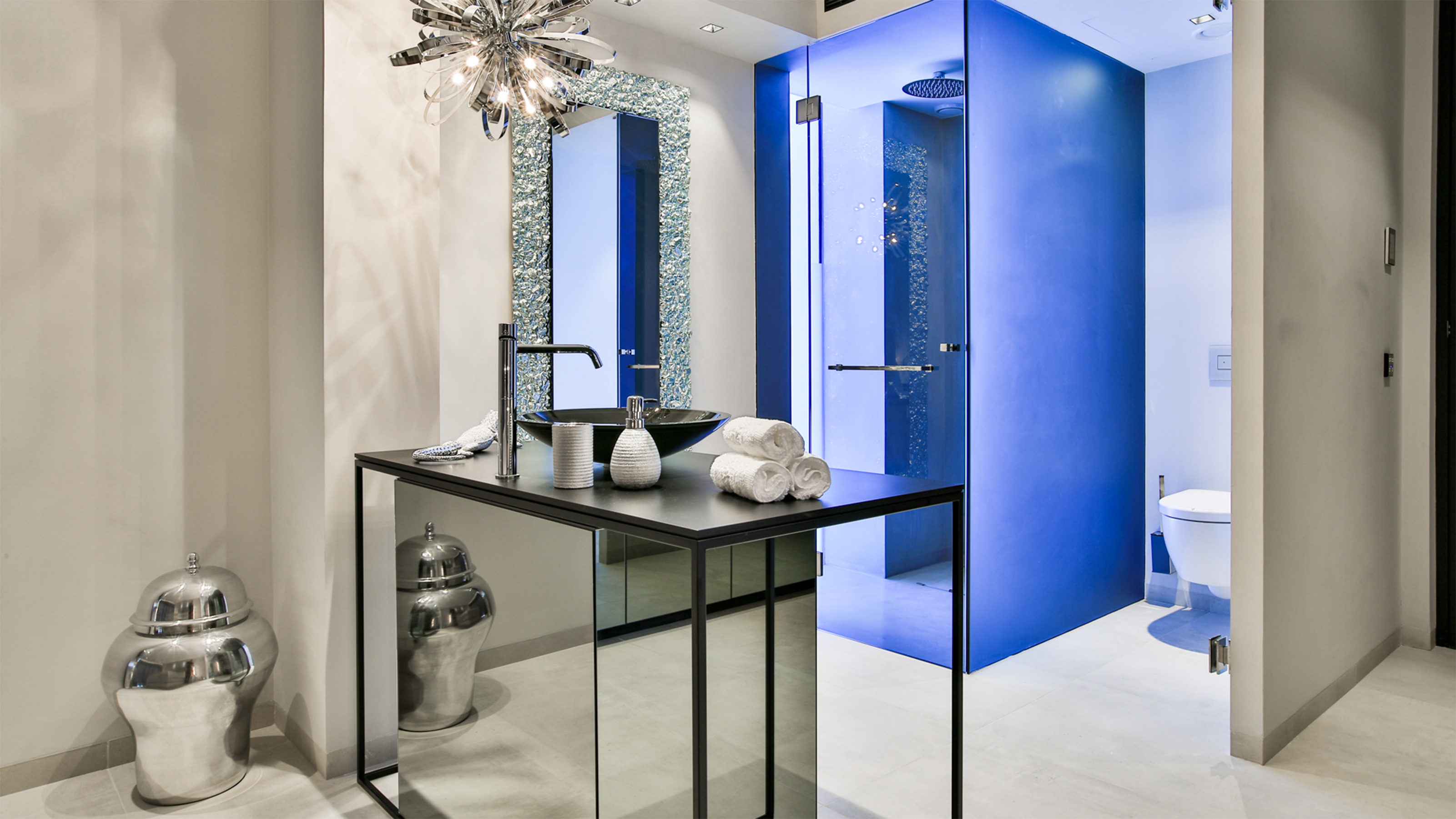 Light floor tiles in a luxurious bathroom with a blue shower wall.
