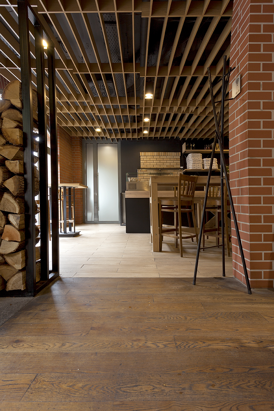 Modern room with dark wood-look and light floor tiles, surrounded by brick walls.
