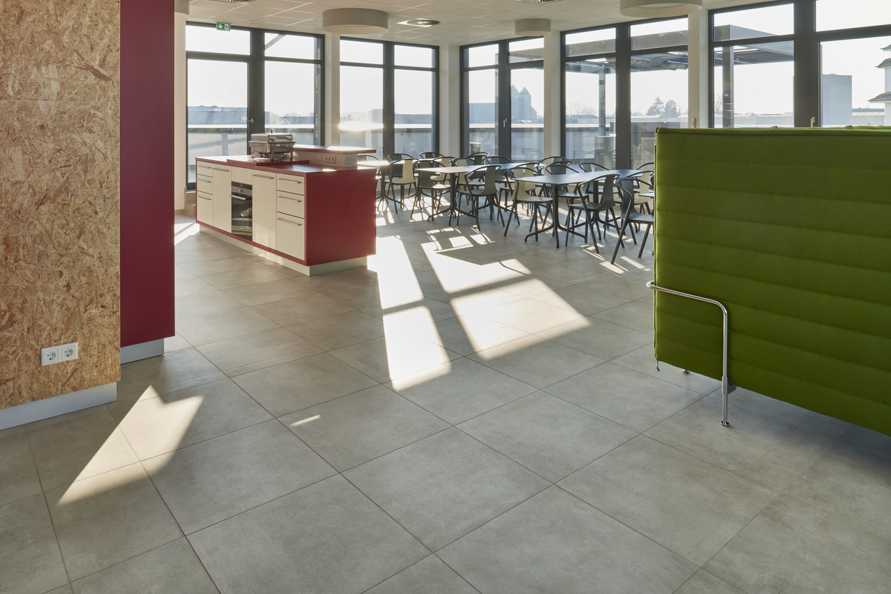 Light, large-format concrete-effect floor tiles in a modern office.