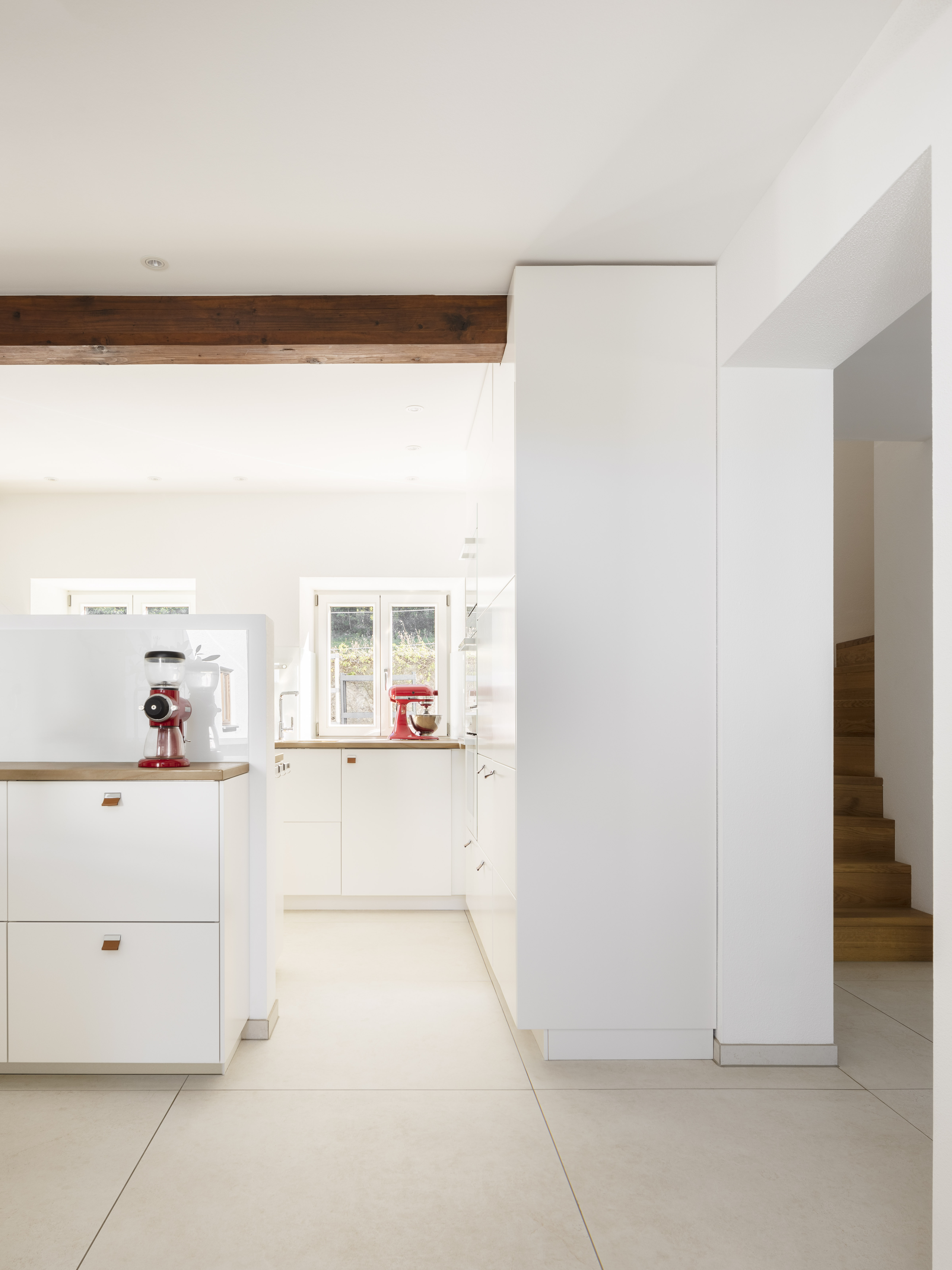 Light floor tiles in a modern, open kitchen with wooden accents.