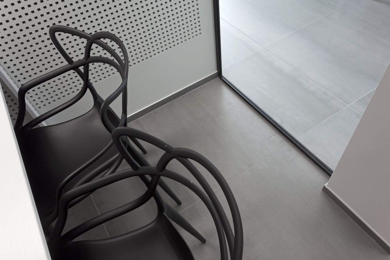 Grey floor tiles in a modern interior with designer chairs.