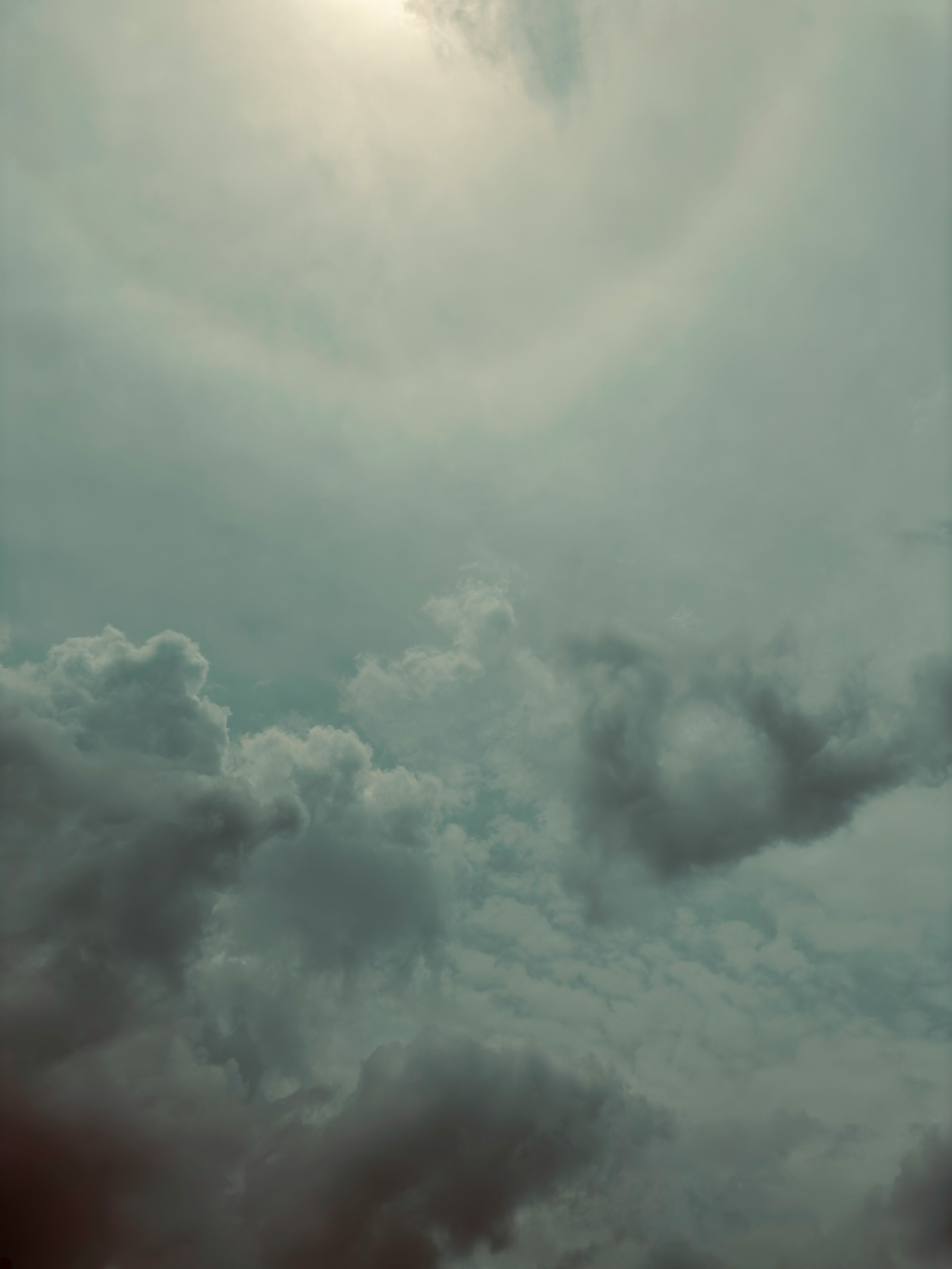 Atmospheric sky with dense clouds and a sun halo.