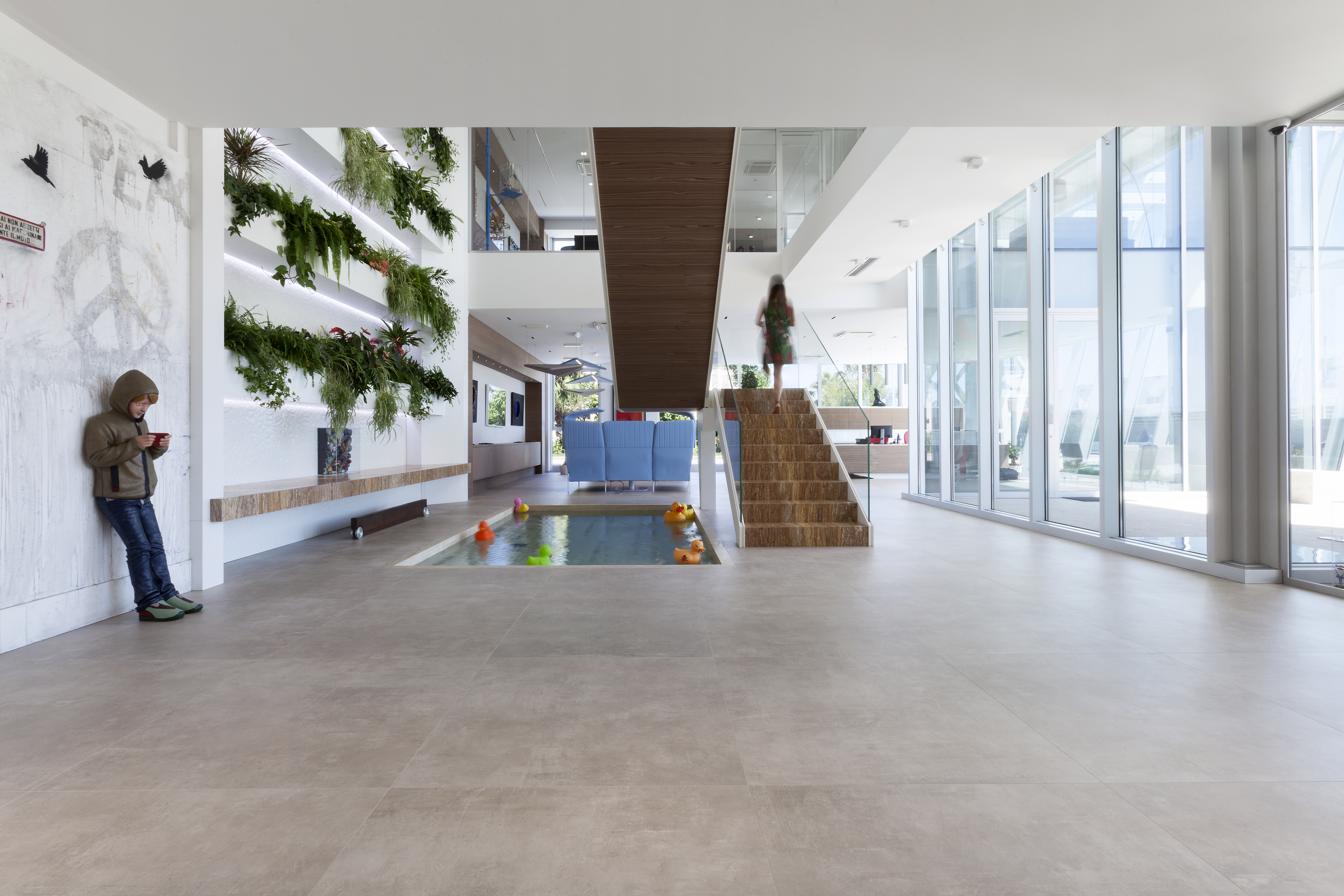 Spacious, bright interior with modern tiles, wooden staircase, and vertical garden.