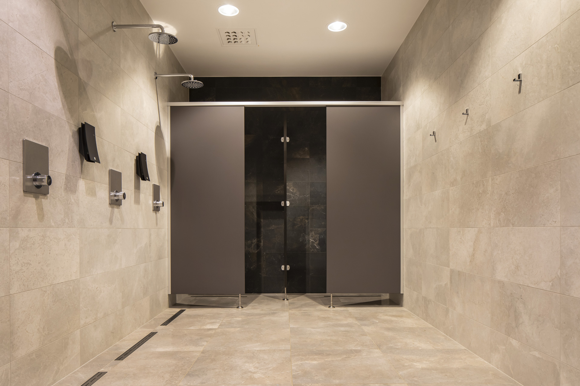 Modern shower area with light, large-format tiles on walls and floor.
