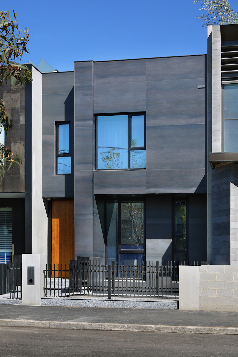 Modern house facade with high-quality, dark tiles and wooden door.