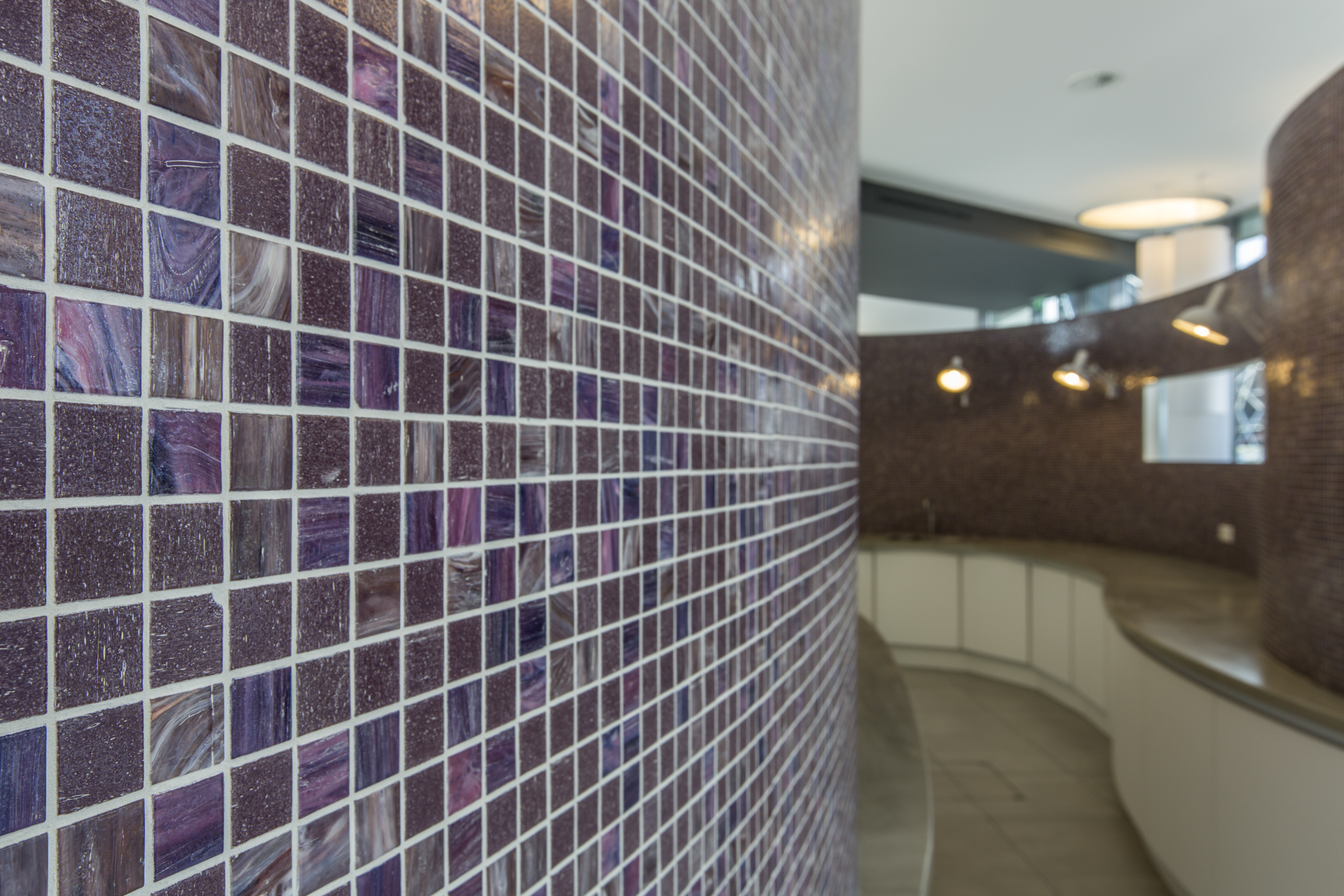 Shimmering violet mosaic tiles on an elegantly curved wall.