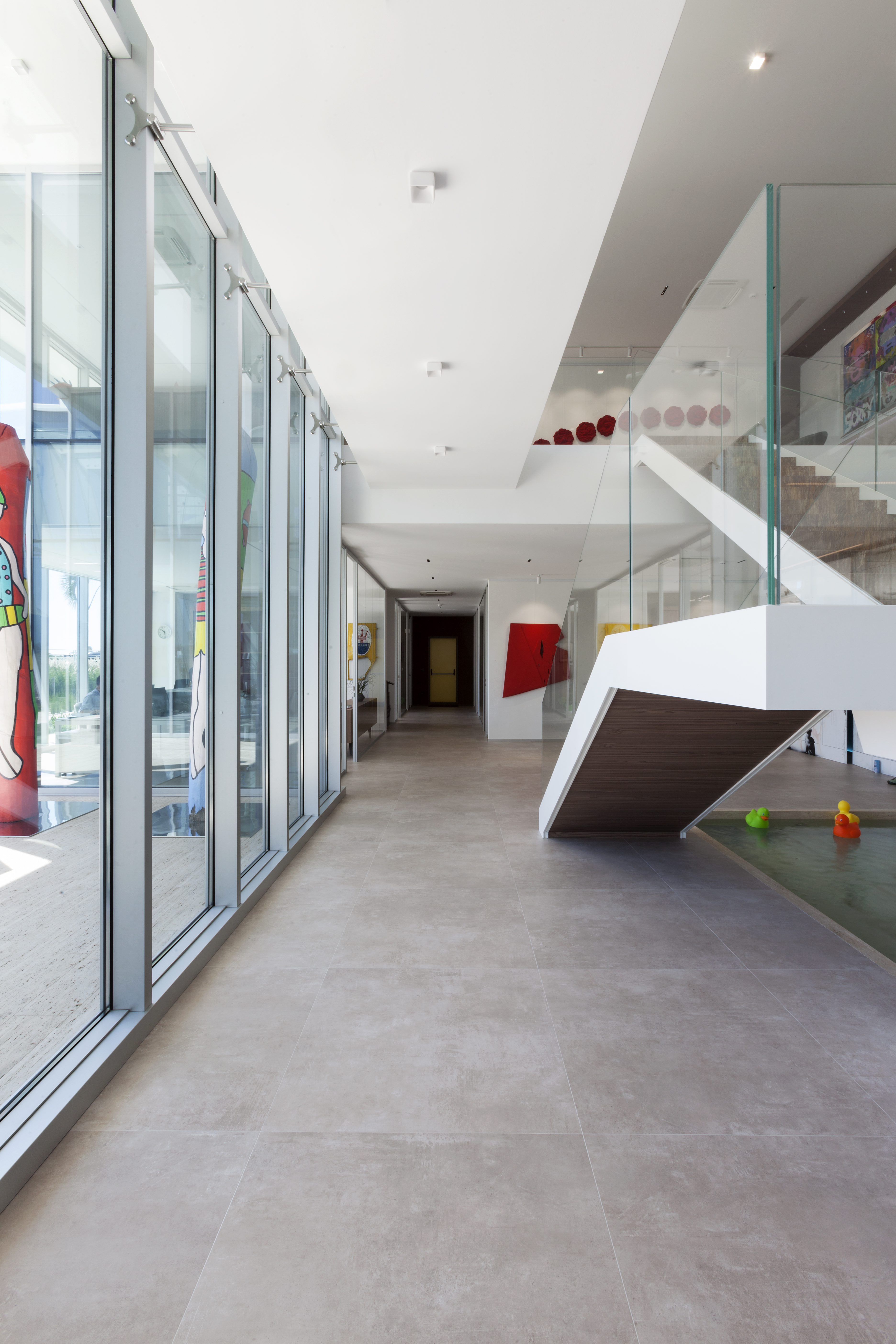 Large-format, light-grey tiles in a modern, light-filled entrance area.