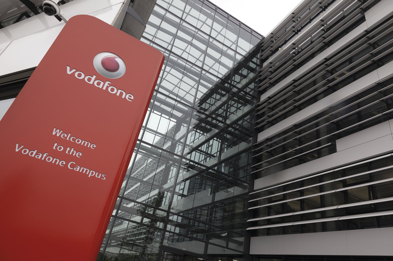 Red Vodafone sign with "Welcome to the Vodafone Campus" in front of a modern glass building.