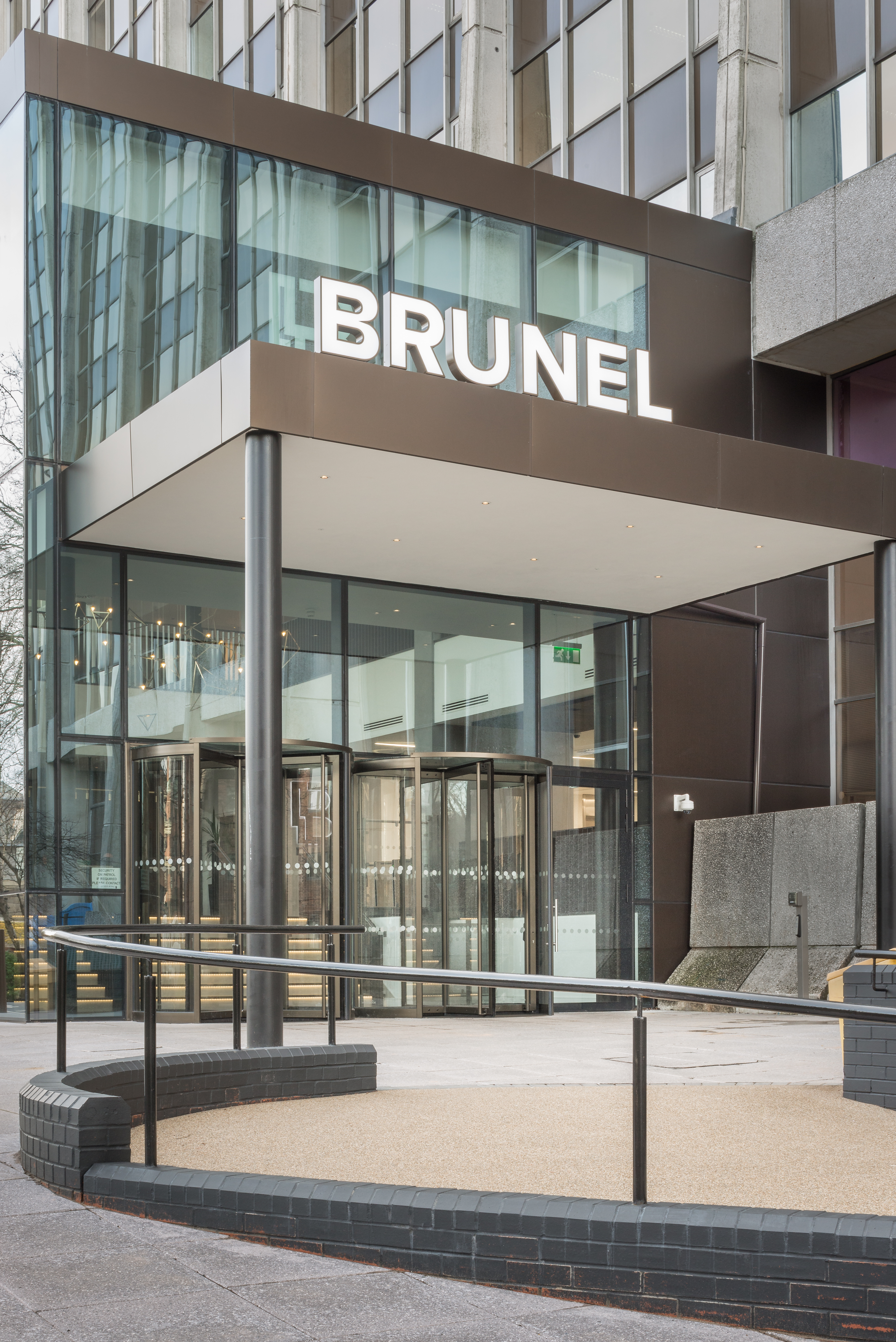 BRUNEL building entrance, glass facade, and light outdoor tiles.