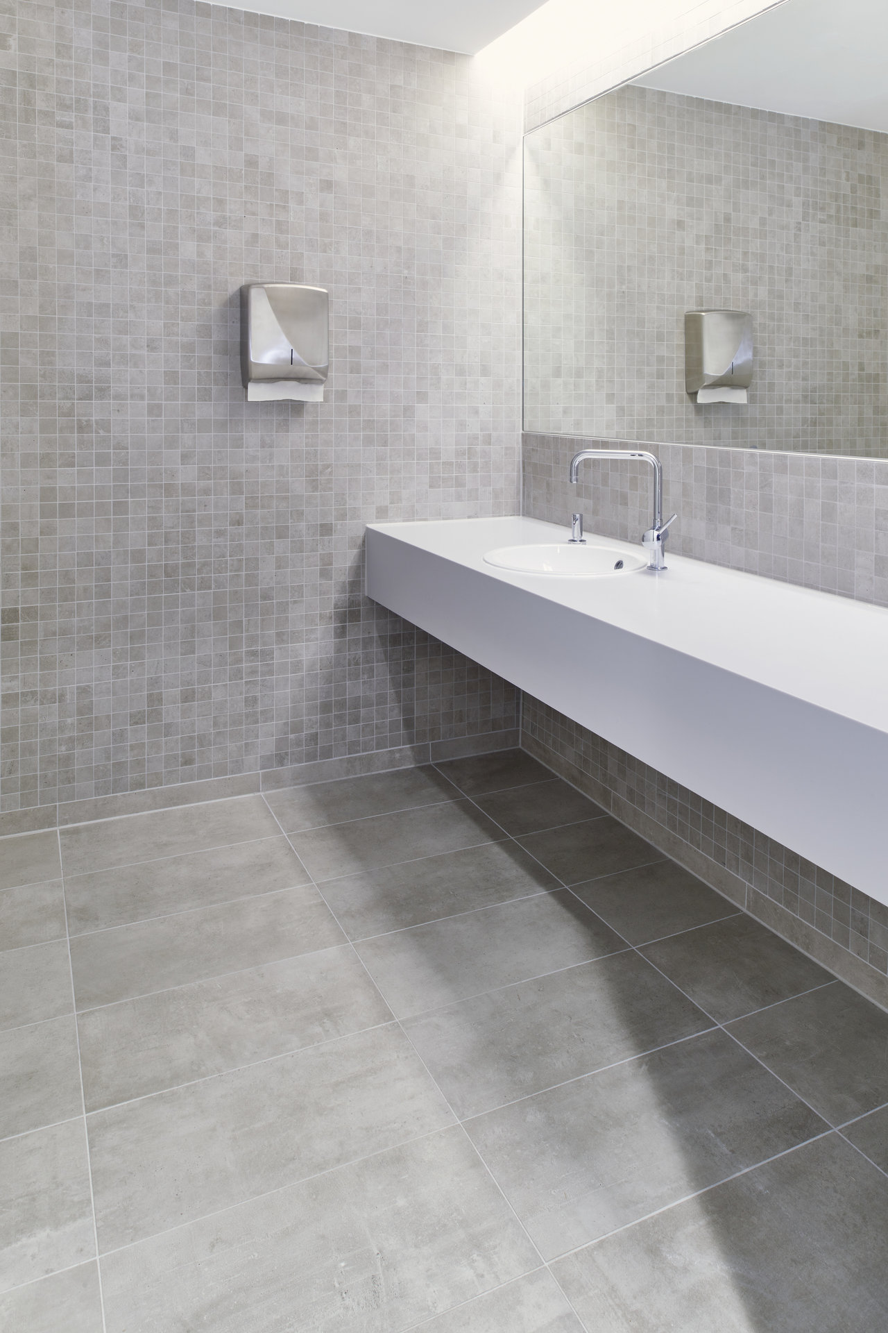 Modern bathroom with grey mosaic wall tiles and large-format floor tiles.