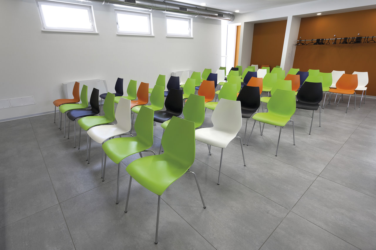 Large-format grey tiles in a modern conference room with colourful chairs.