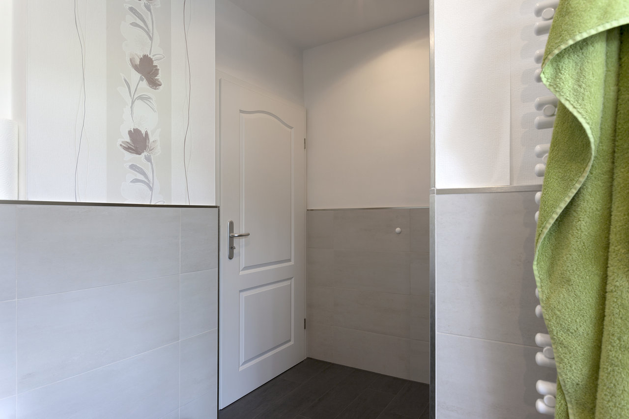 Light wall and dark floor tiles in a modern interior with floral wallpaper.
