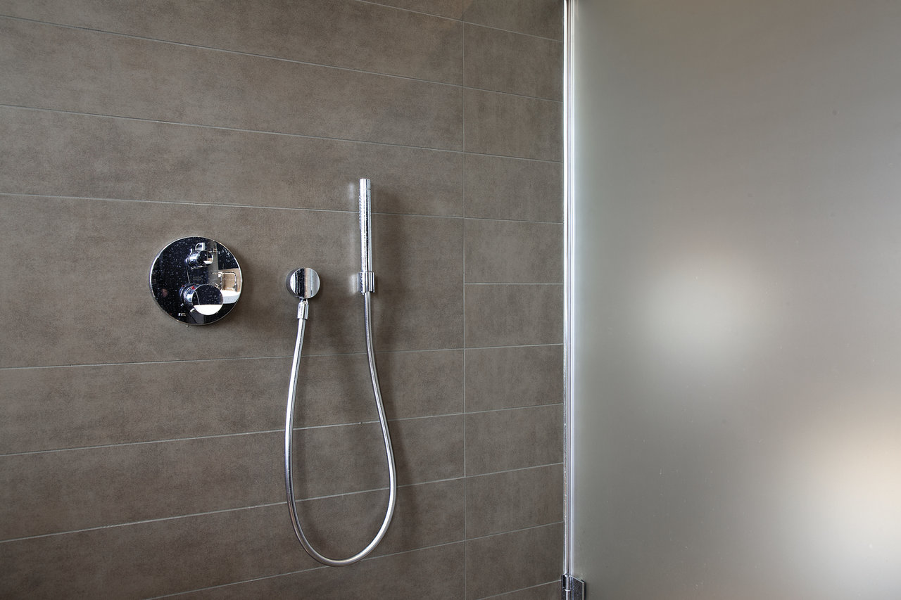 High-quality dark grey porcelain tiles in shower with glass wall.