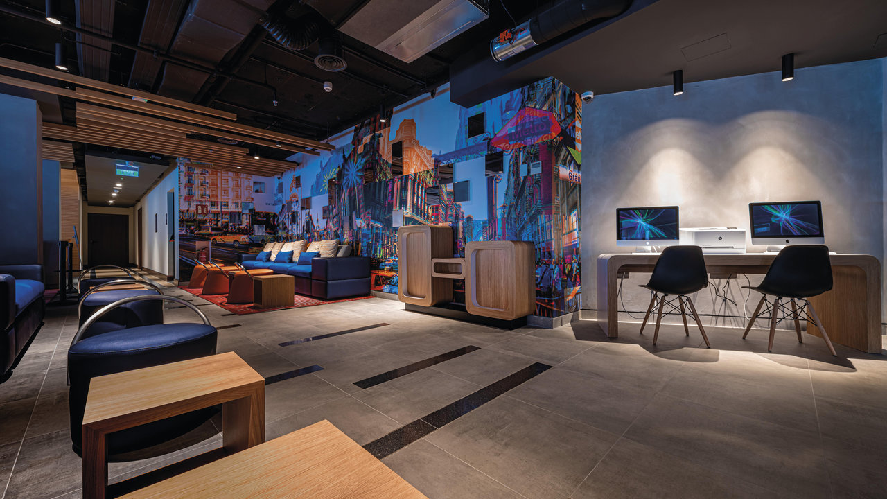 Large-format grey tiles in a modern lounge area with colourful wall design.