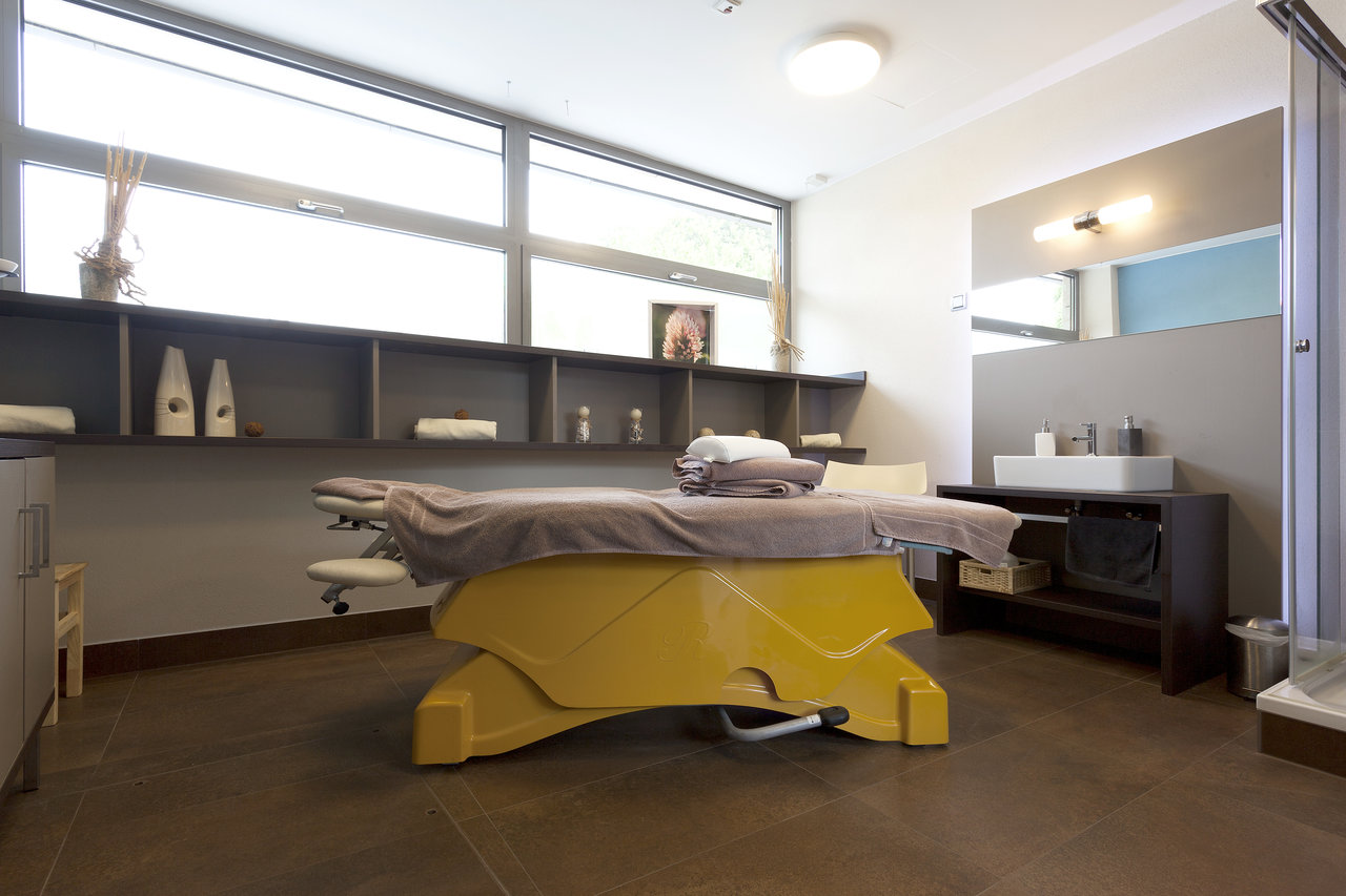 Dark, premium floor tiles in a spa area with a massage bed.