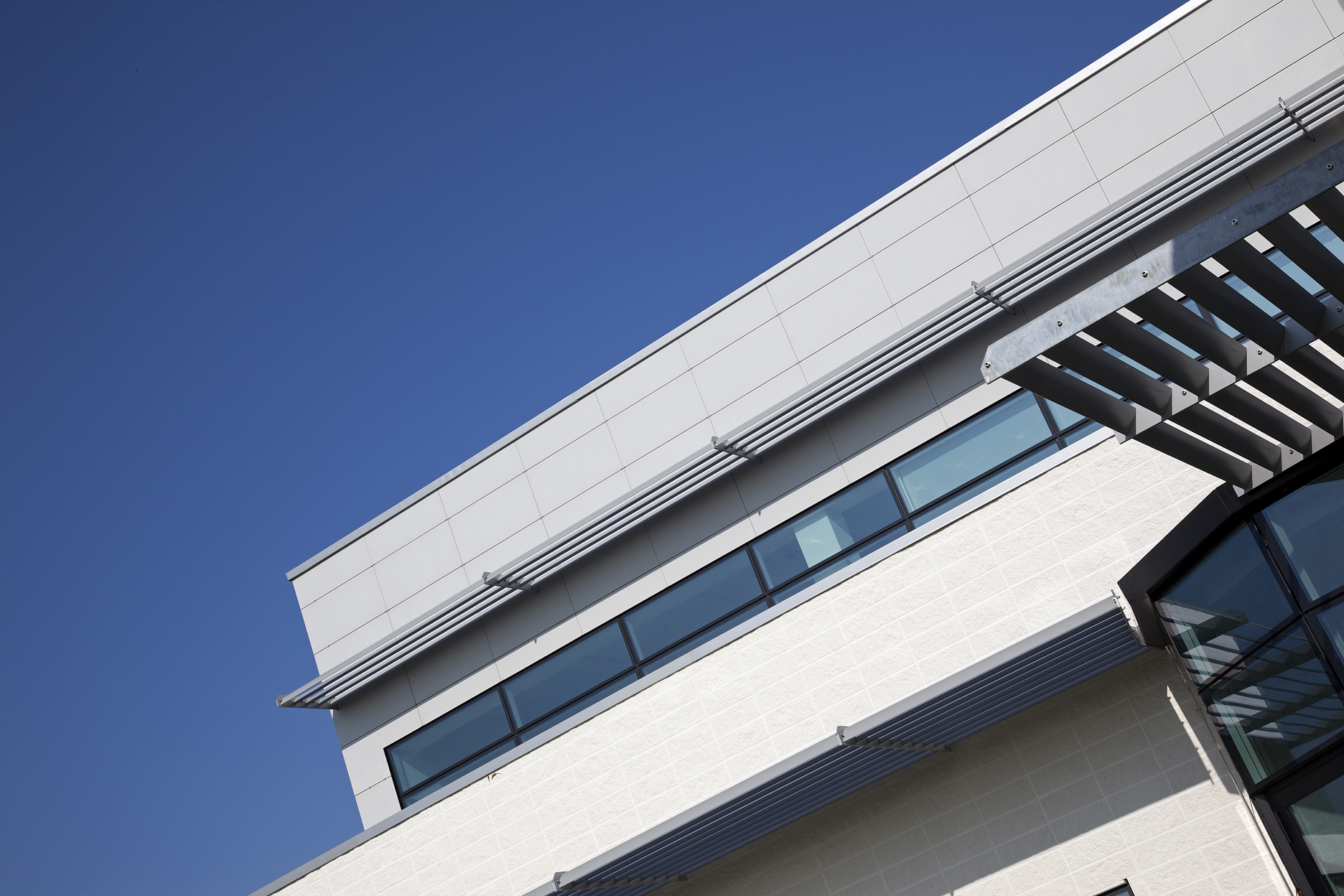 Modern building facade with clean lines and large windows under a blue sky.