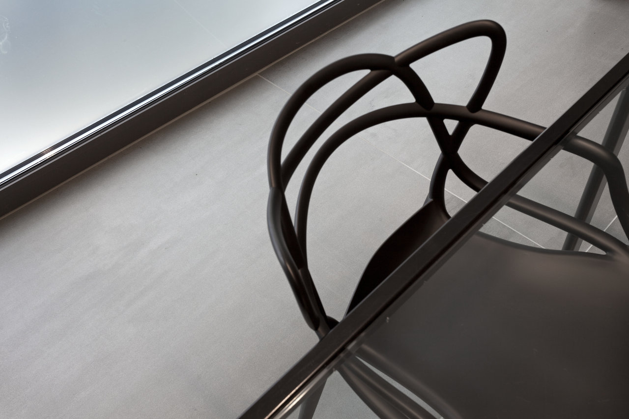 Modern light grey indoor floor tiles with dark furniture.