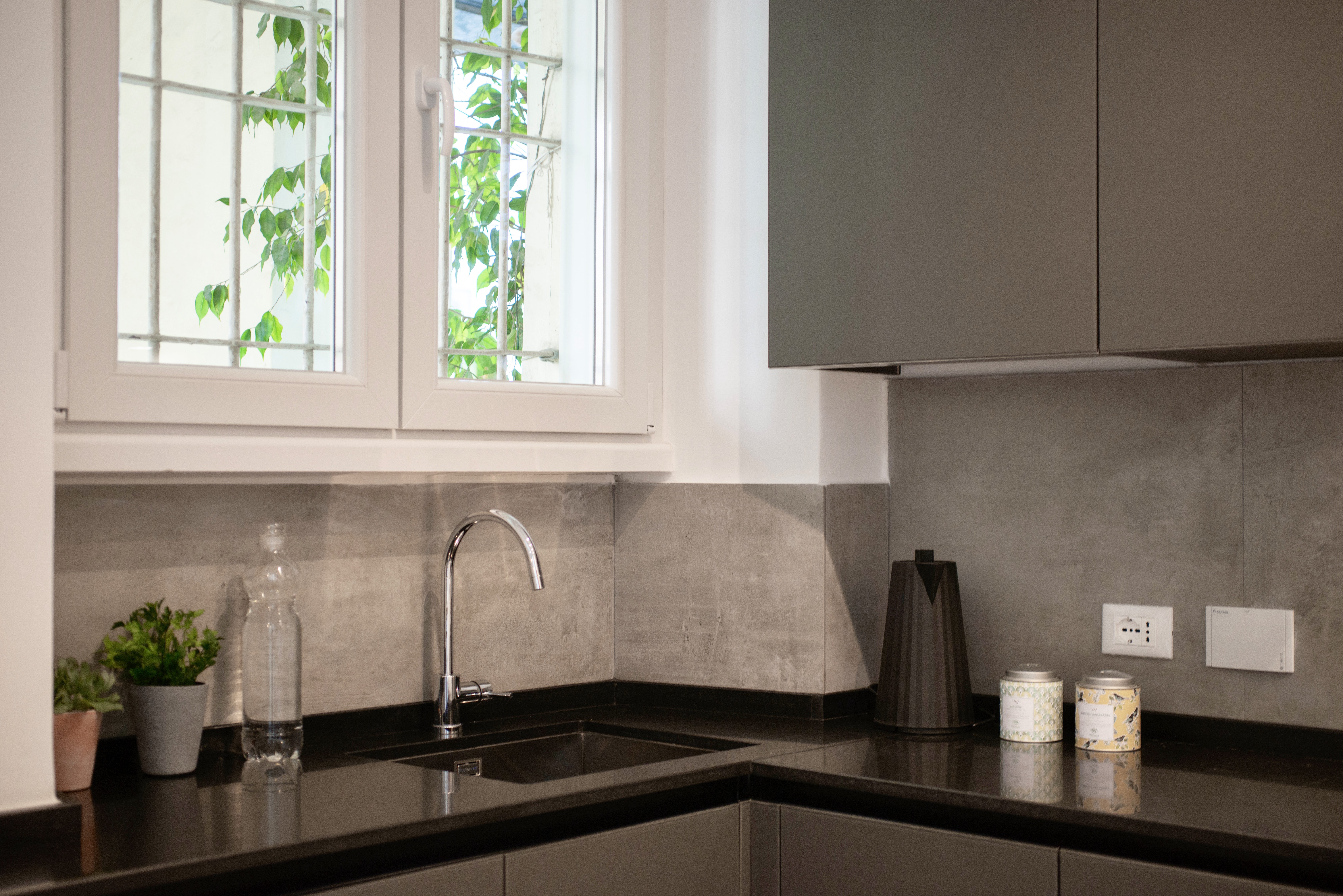 Modern kitchen with grey wall tiles and black worktop.