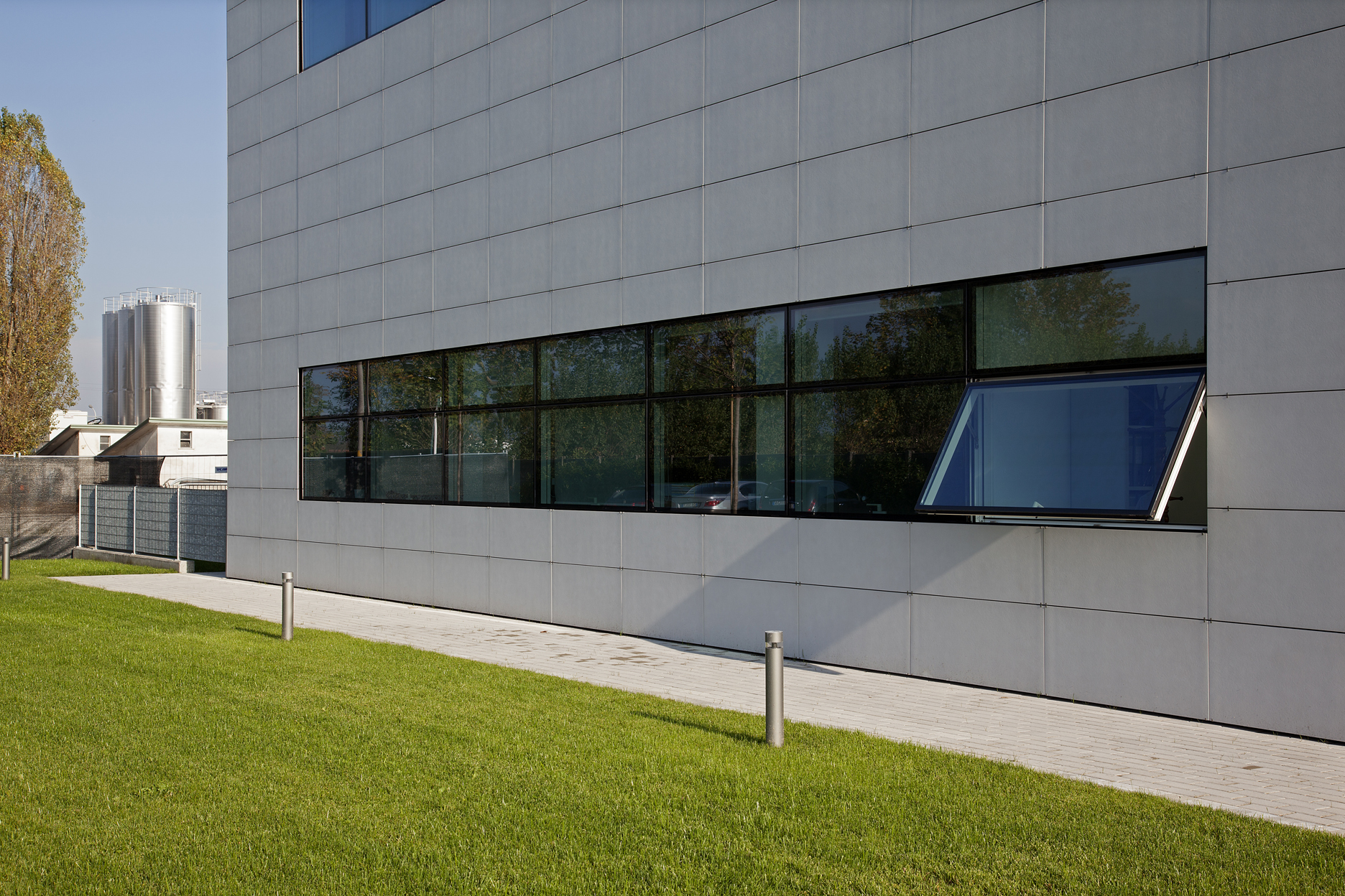 High-quality grey facade tiles on a modern building with greenery.