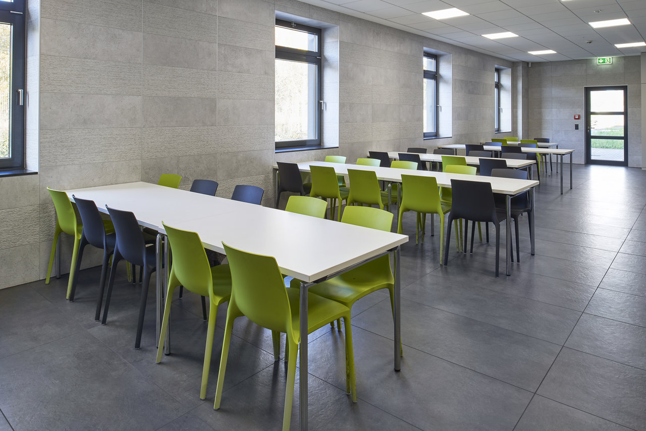 Large-format grey tiles on floor and walls of a modern communal area.