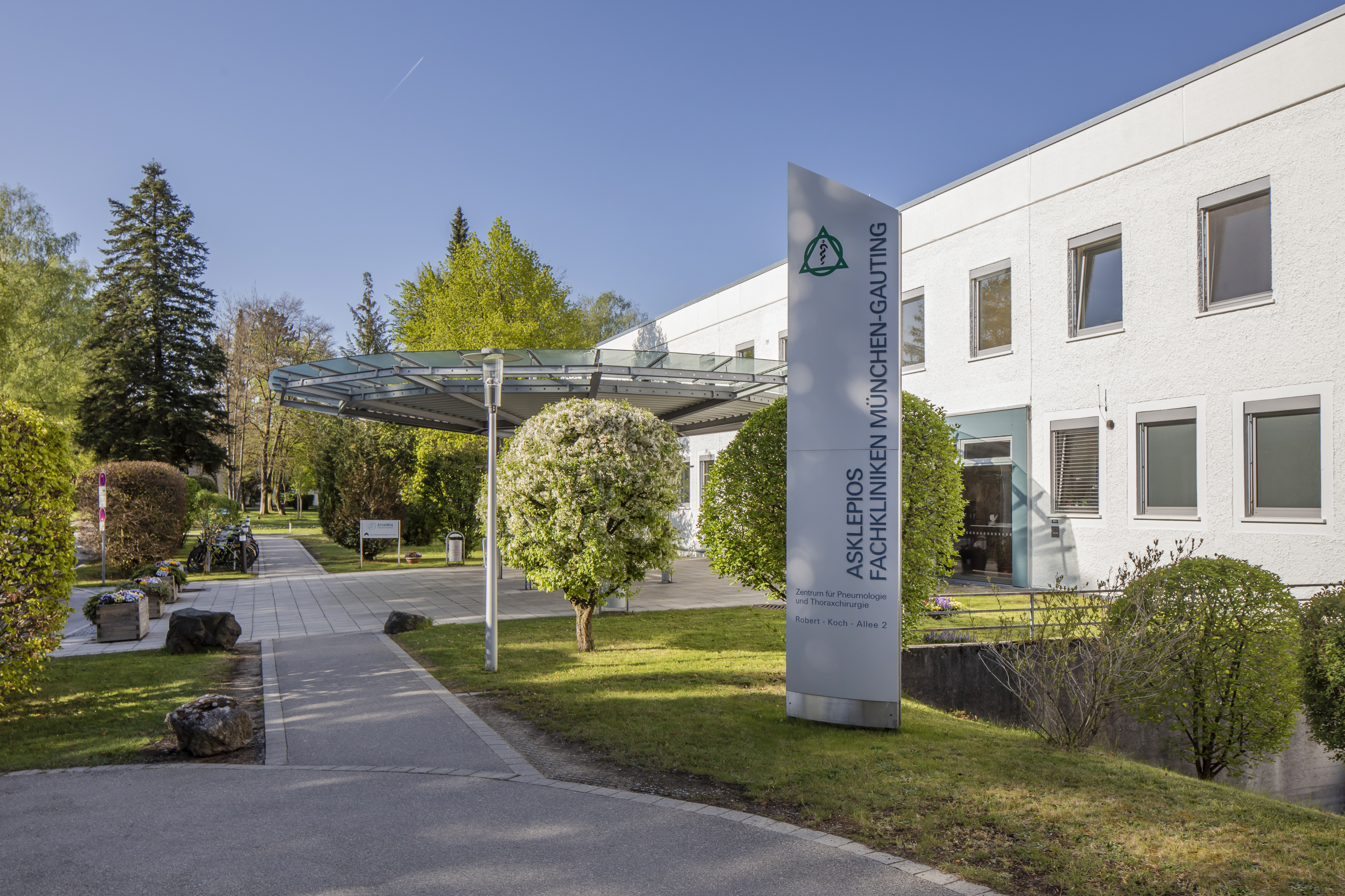 Exterior view of Asklepios Specialist Clinics Munich-Gauting, with entrance and green spaces.