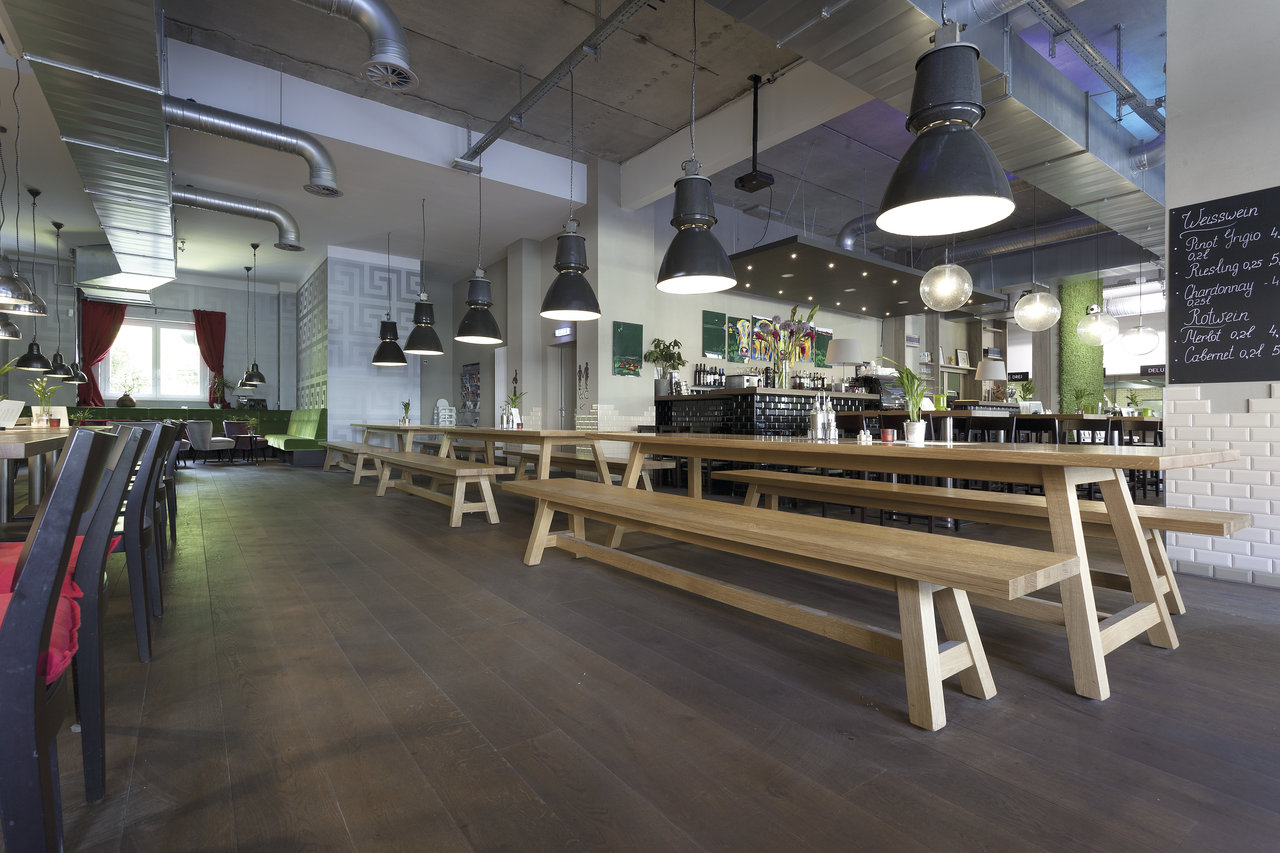 Dark wood-look tile floor in a modern restaurant with long wooden tables.
