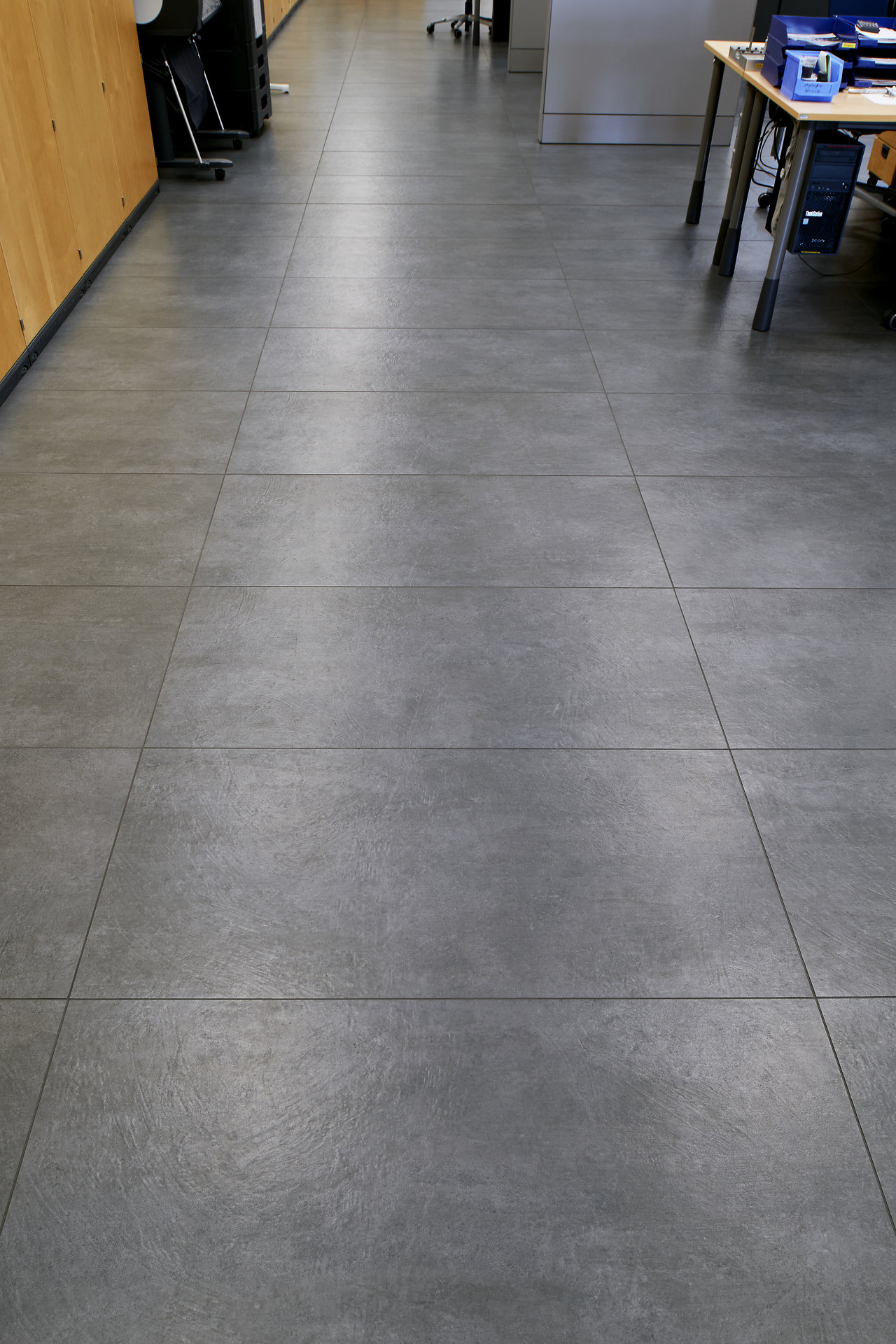 Large-format anthracite floor tiles with concrete look.