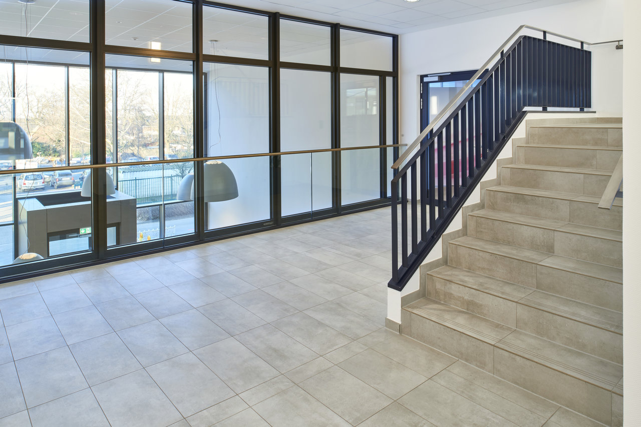 Large-format, light grey tiles on floor and stairs in a modern setting.