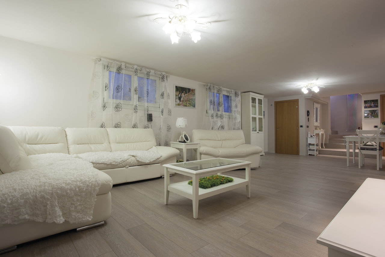 Modern living area with light grey tiled floor and white furnishings.