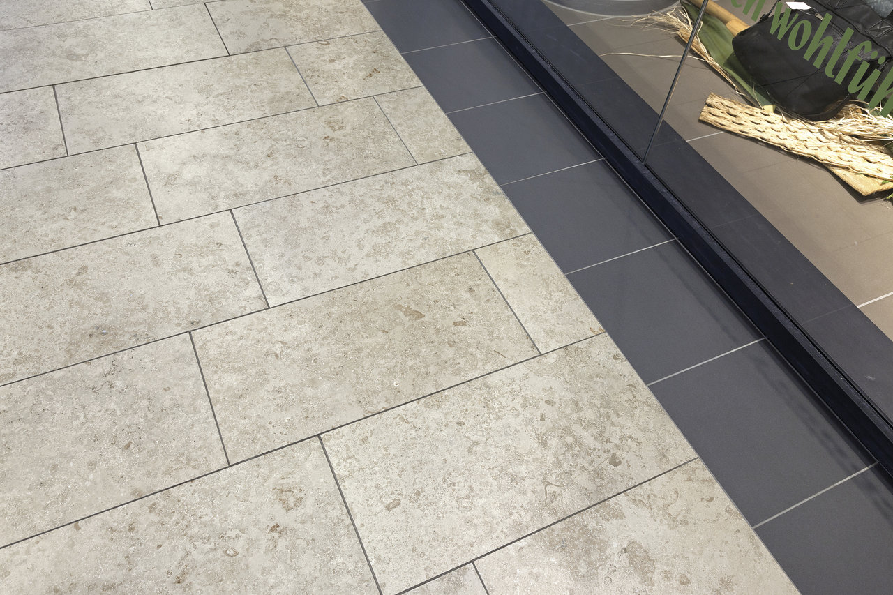 Light outdoor stone-effect tiles combined with dark transition tiles.