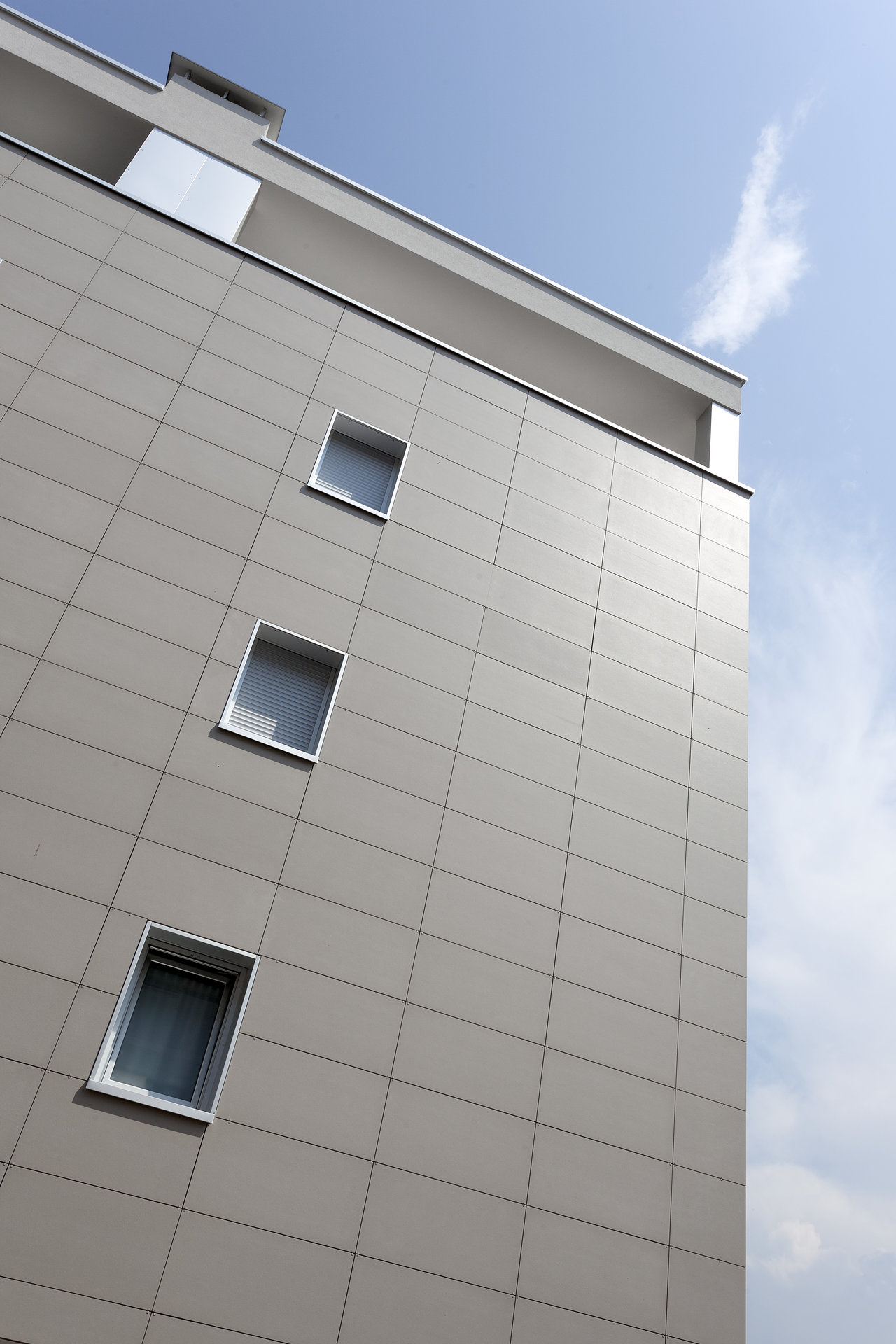 Large-format, light-grey outdoor tiles on a modern facade.