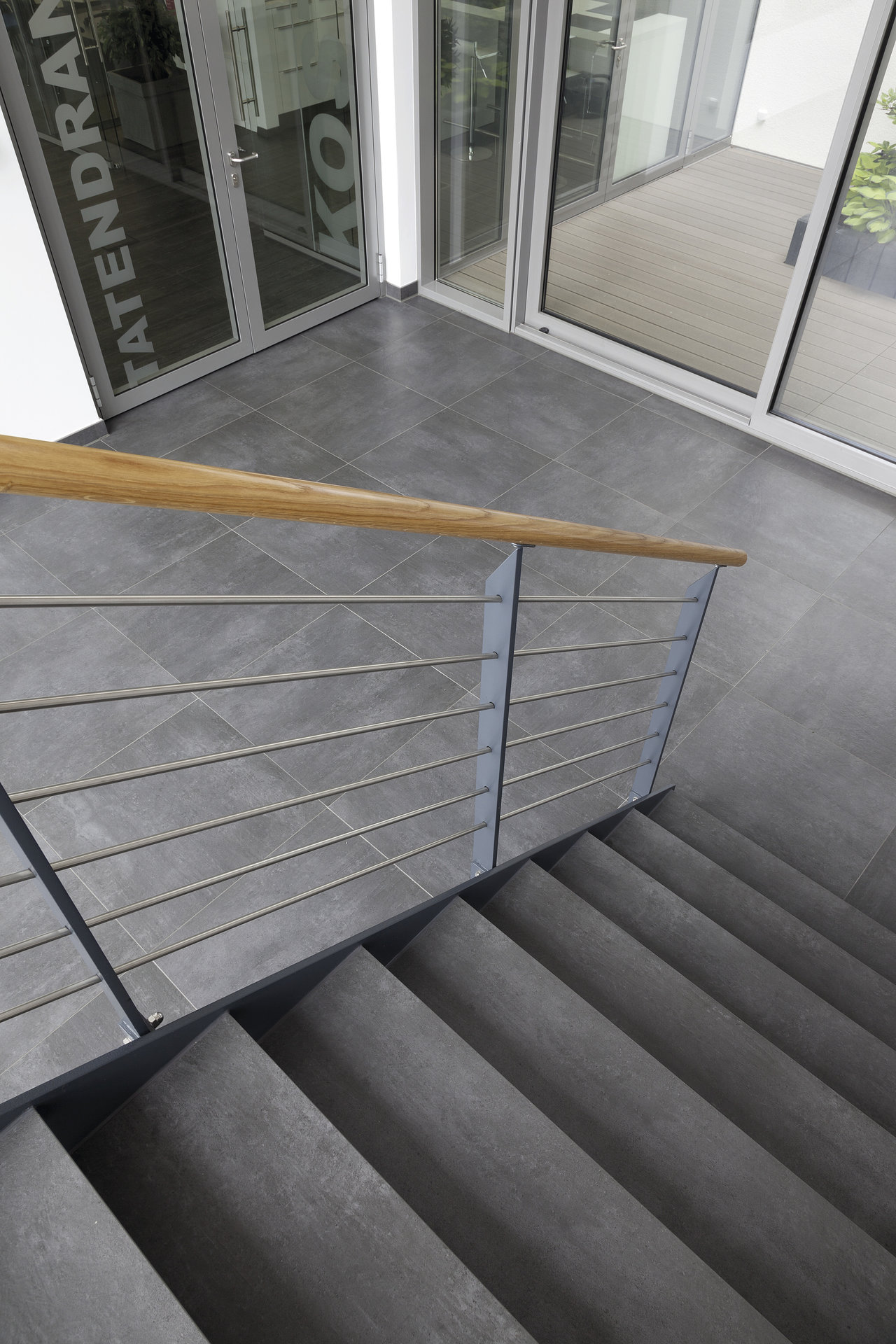 Dark grey tiles on stairs and floor in a modern entrance area.