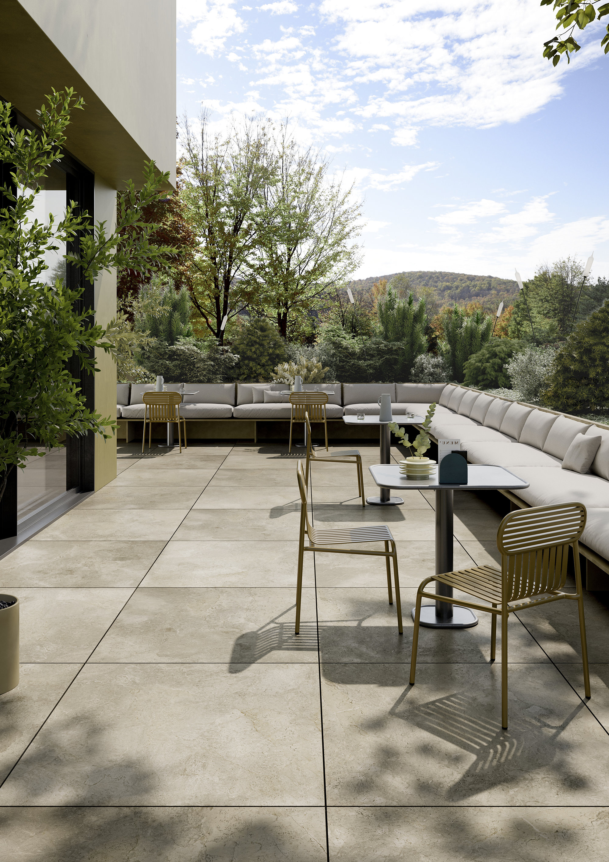 Light, large-format outdoor tiles on a modern terrace with lounge furniture and lush greenery.