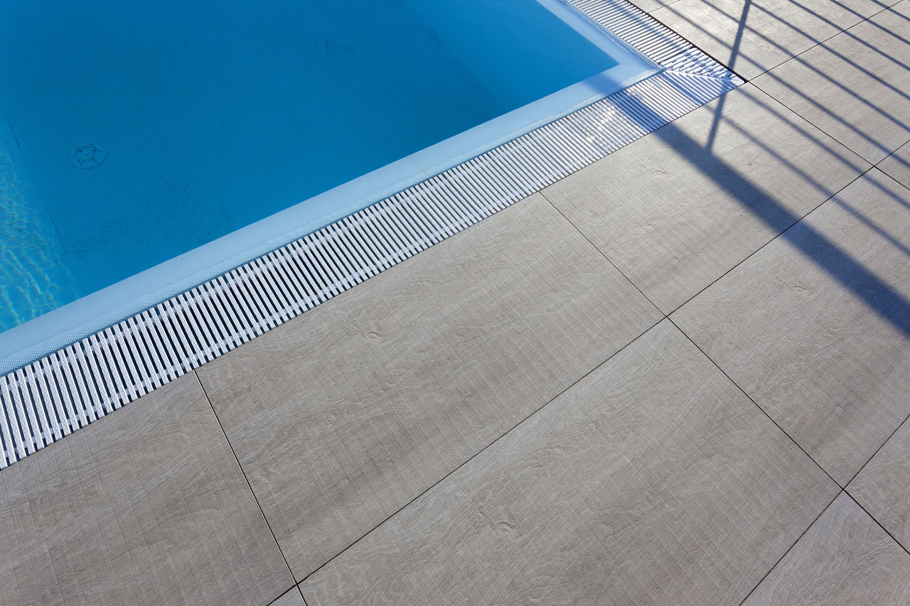 High-quality grey outdoor tiles at the poolside with a drainage channel.