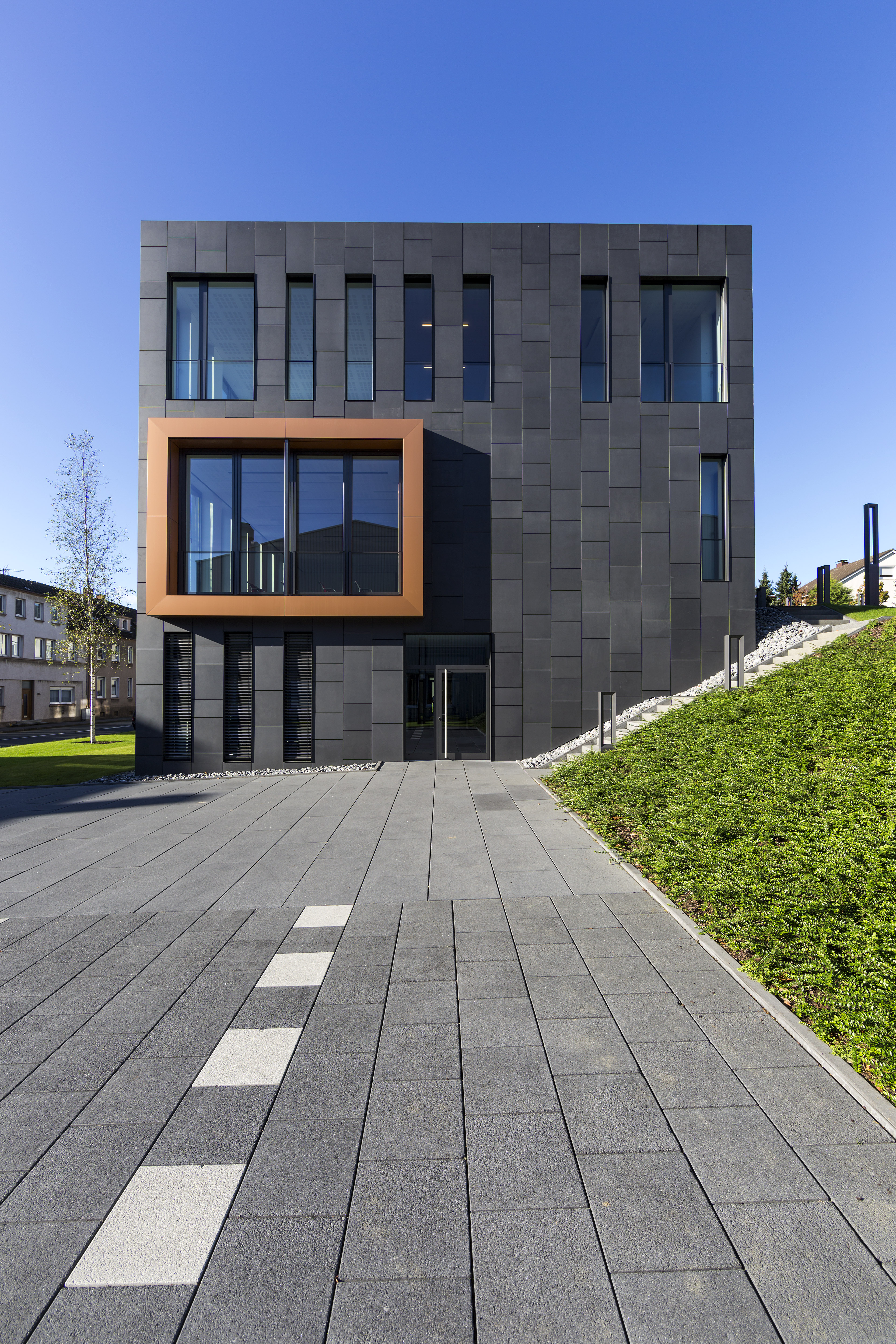 Modern outdoor tiles in front of a building with a dark tiled facade.