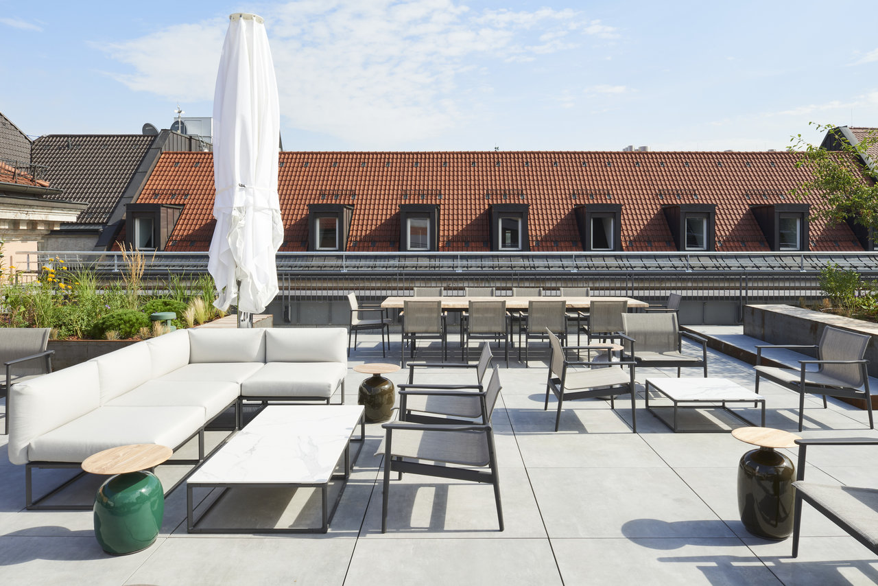 Light outdoor tiles on a stylish roof terrace with lounge furniture and dining area.
