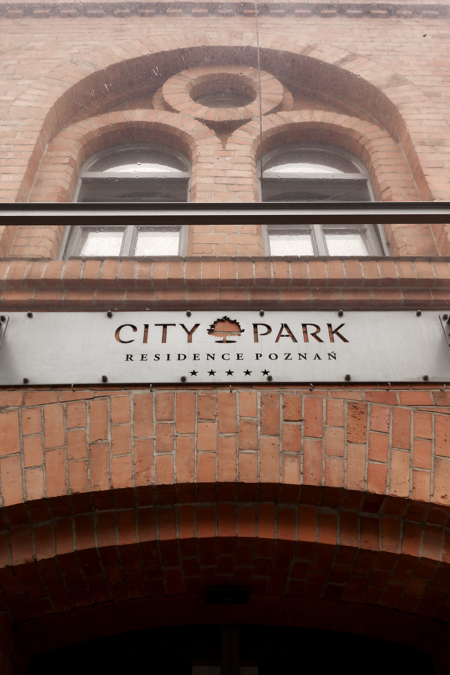 5-star 'City Park Residence Poznan' sign on brick facade.